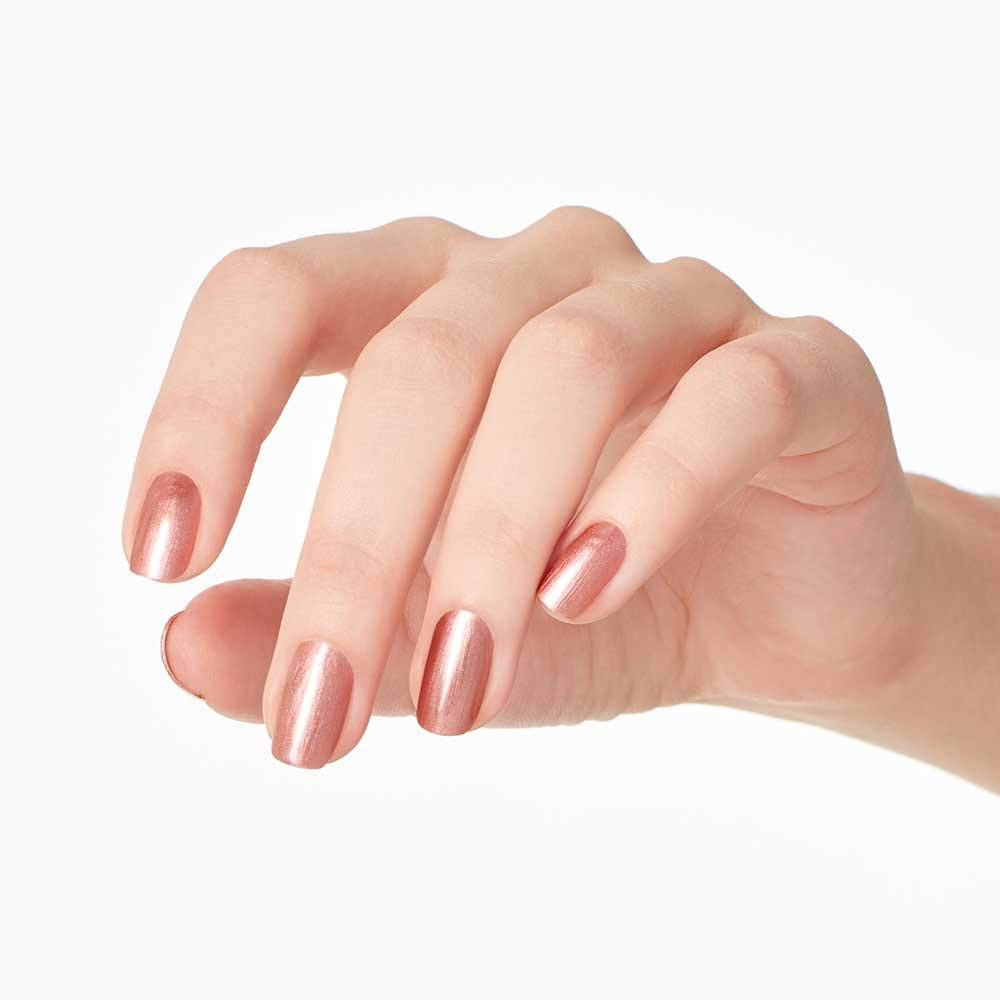 Hand mit lackierten Nägeln. Goldfarbener Nagellack auf fünf Fingernägeln.