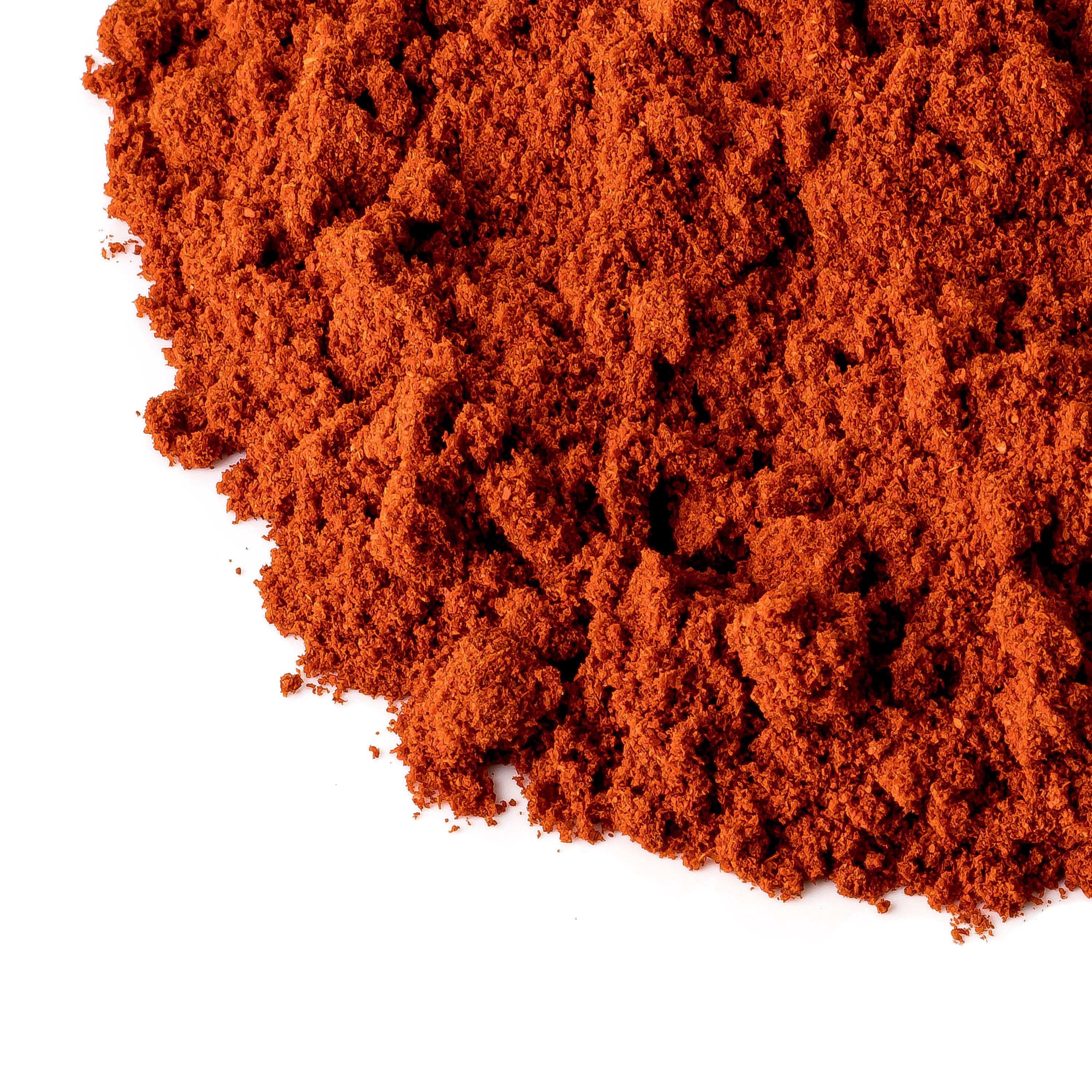 Nahaufnahme von Paprikapulver. Rote Farbe, grobe Textur. Weißer Hintergrund.