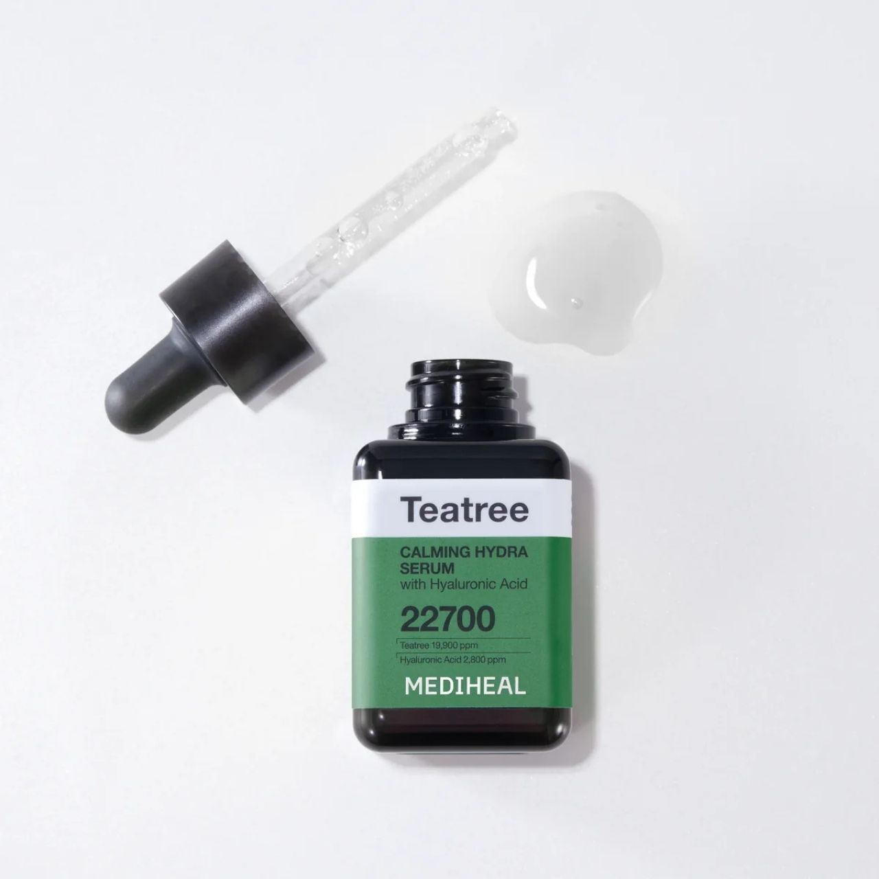 MEDIHEAL Teebaumöl Beruhigendes Hydra-Serum Flasche mit Pipette und Serum-Tropfen daneben.