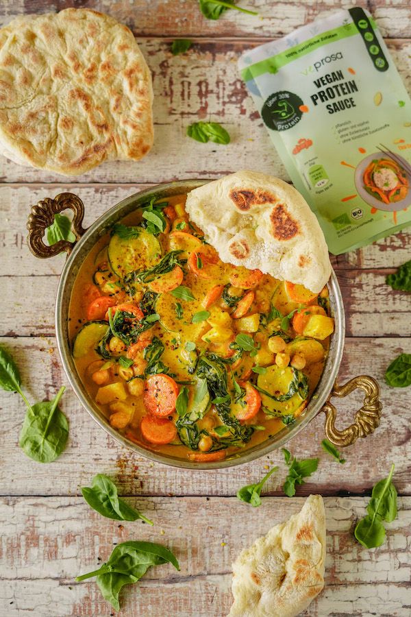 Schüssel mit Thai Curry, Fladenbrot und frischen Kräutern. Verpackung VEPROSA Bio-Saucenpulver im Hintergrund.