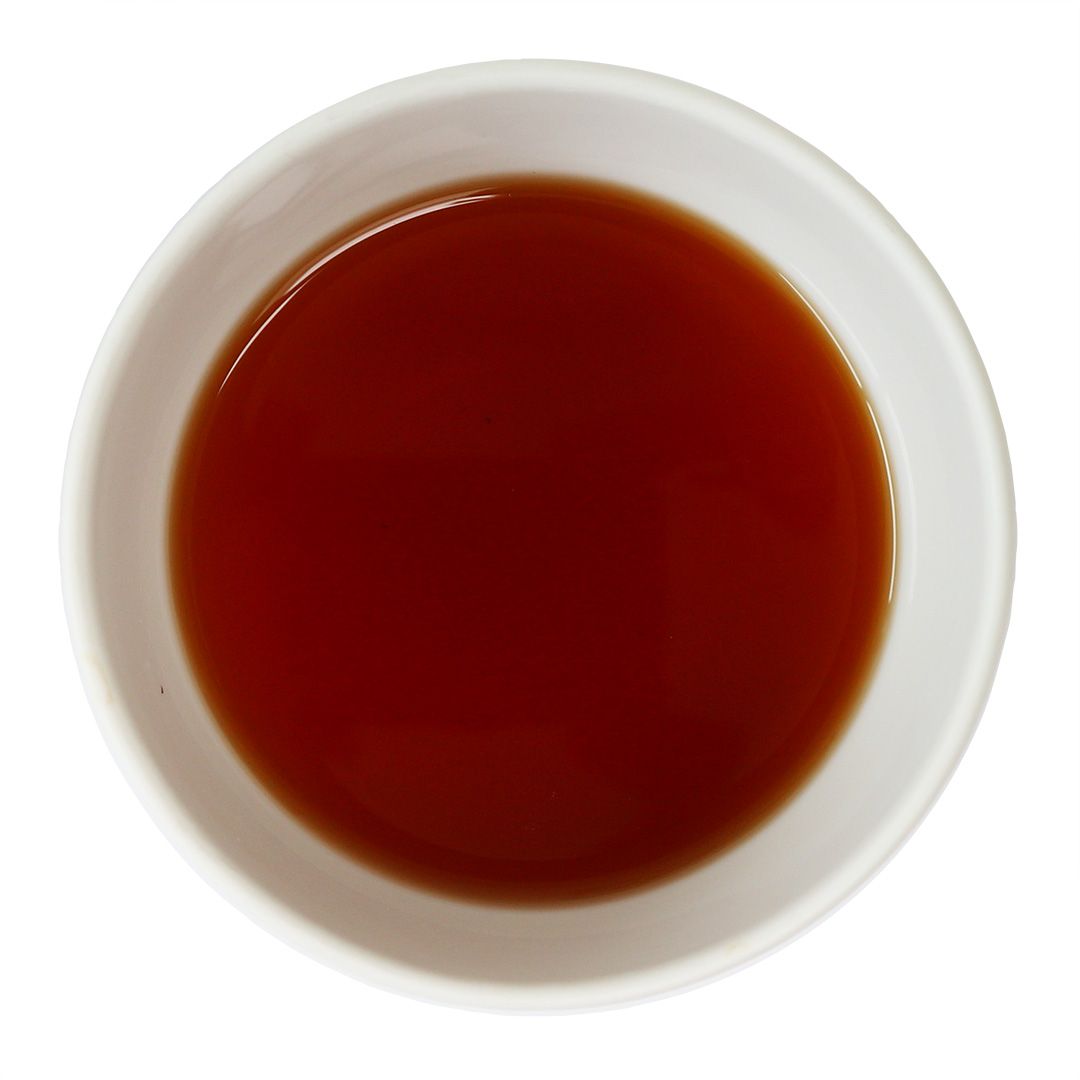 Weisse Schale mit rotem Tee. Der Tee ist flüssig und von dunkler Farbe.