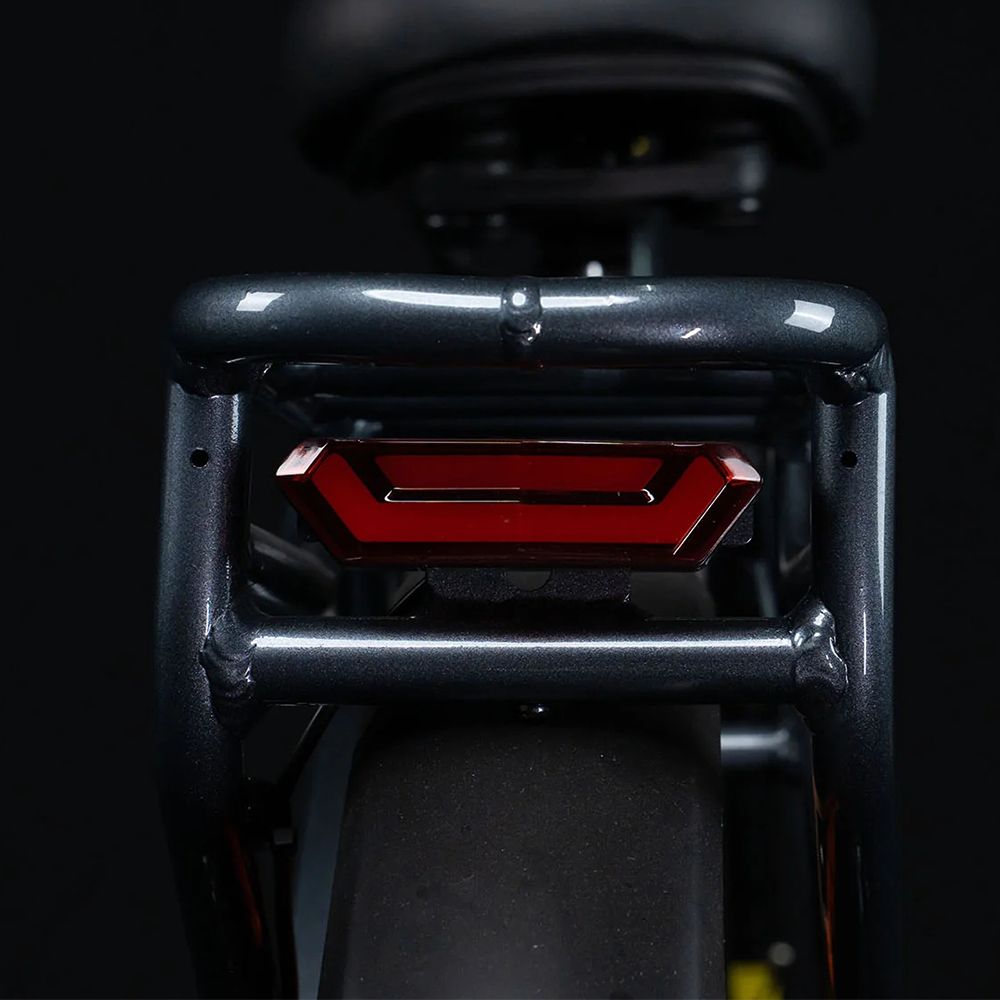 Rücklicht eines E-Bikes, rot und rechteckig, am Gepäckträger befestigt.