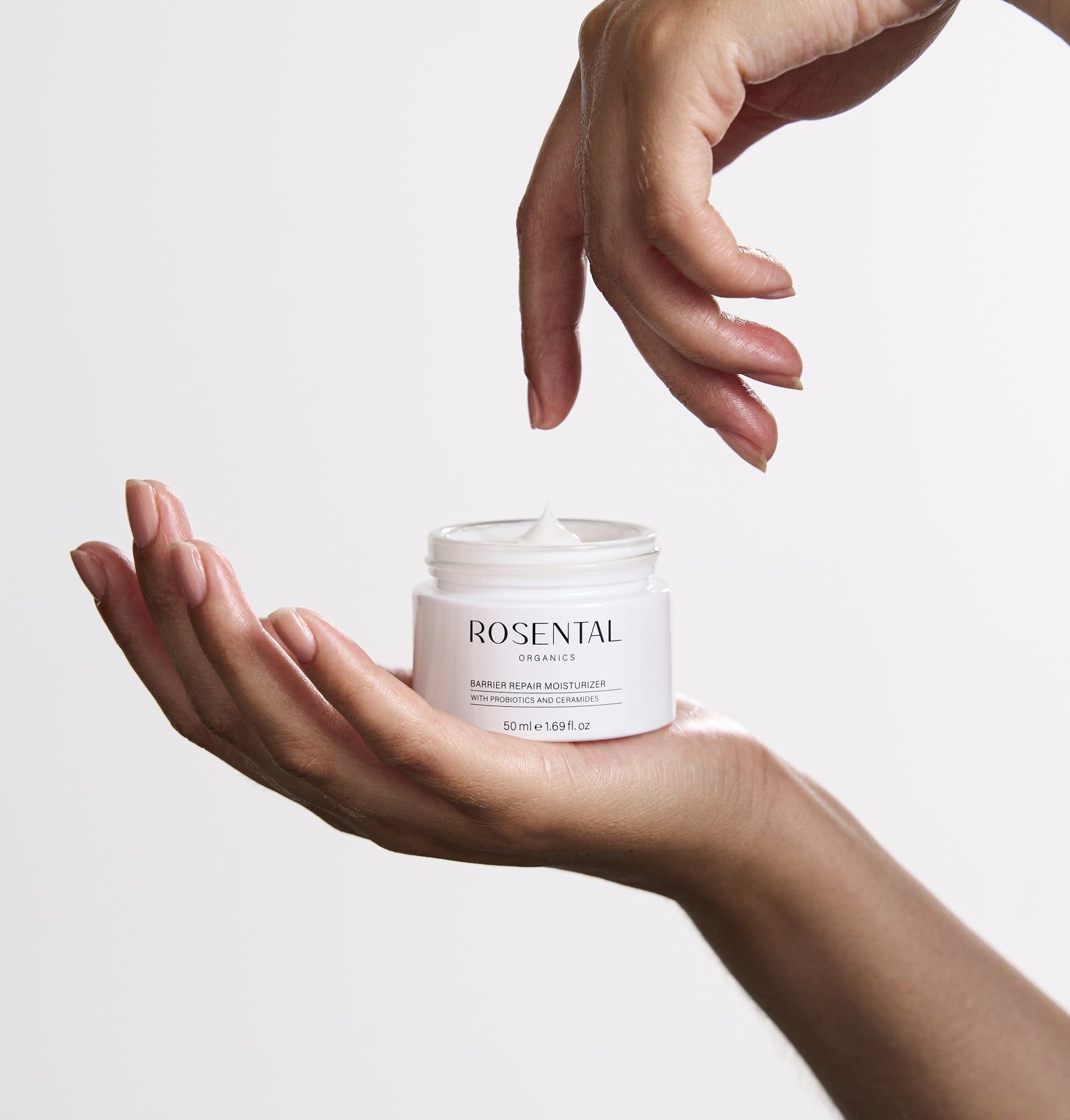 Hände halten Tiegel mit Creme. Aufschrift: Rosental Organics. Produktname: Barrier Repair Moisturizer.
