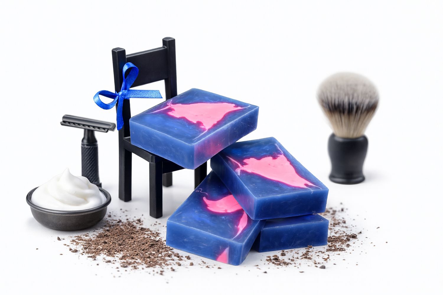 Vier blaue Seifenstücke mit rosa Muster. Daneben Rasierpinsel, Rasiermesser, Stuhl und Rasiercreme.