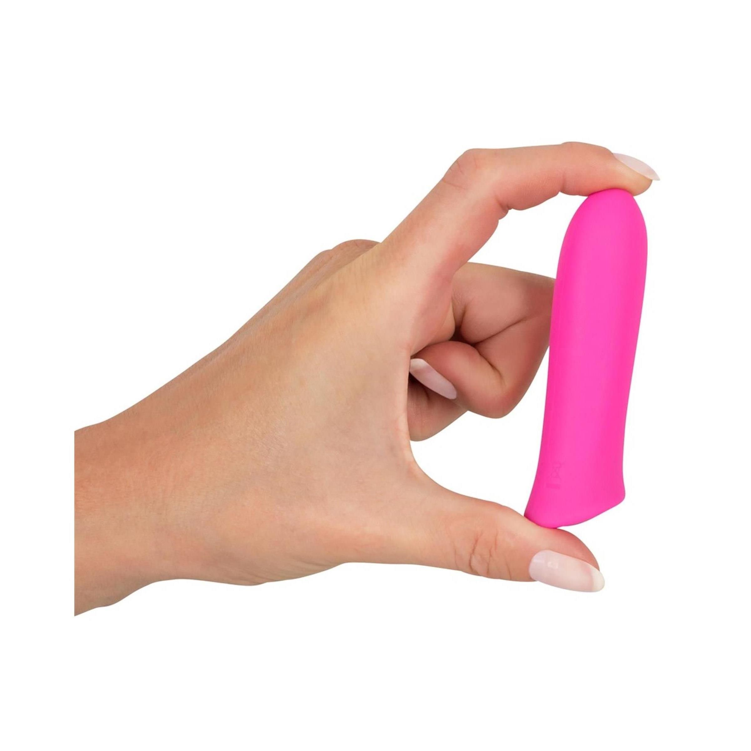 Hand hält pinkfarbenen Vibrator. Zylindrische Form mit abgerundeter Spitze und leicht gebogener Basis.
