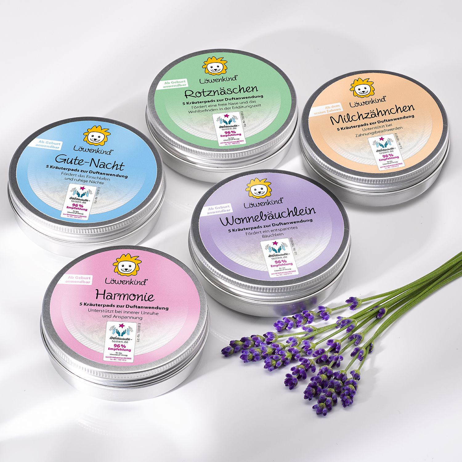 Fünf runde Metalldosen mit Deckel. Aufschrift: LÖWENKIND. Verschiedene Farben: Grün, Orange, Lila, Blau, Rosa. Kräuterpads.