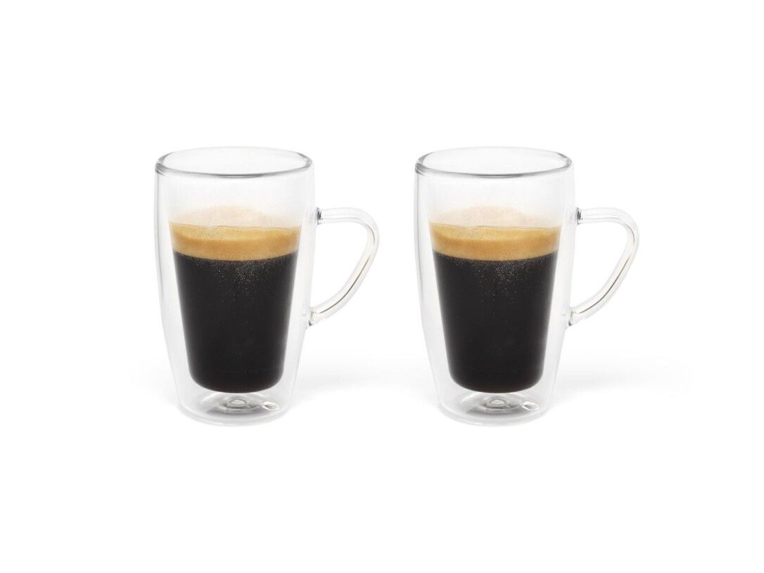 Zwei Espressogläser mit Kaffee gefüllt. Doppelwandig, mit Henkeln. Auf weißem Hintergrund.