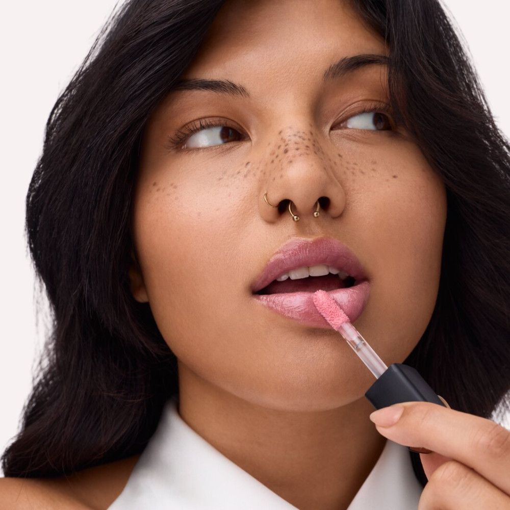 Person trägt Catrice Supreme Lippenfiller Gloss auf. Rosa Lippenstift, Applikator sichtbar. Person mit Piercing.