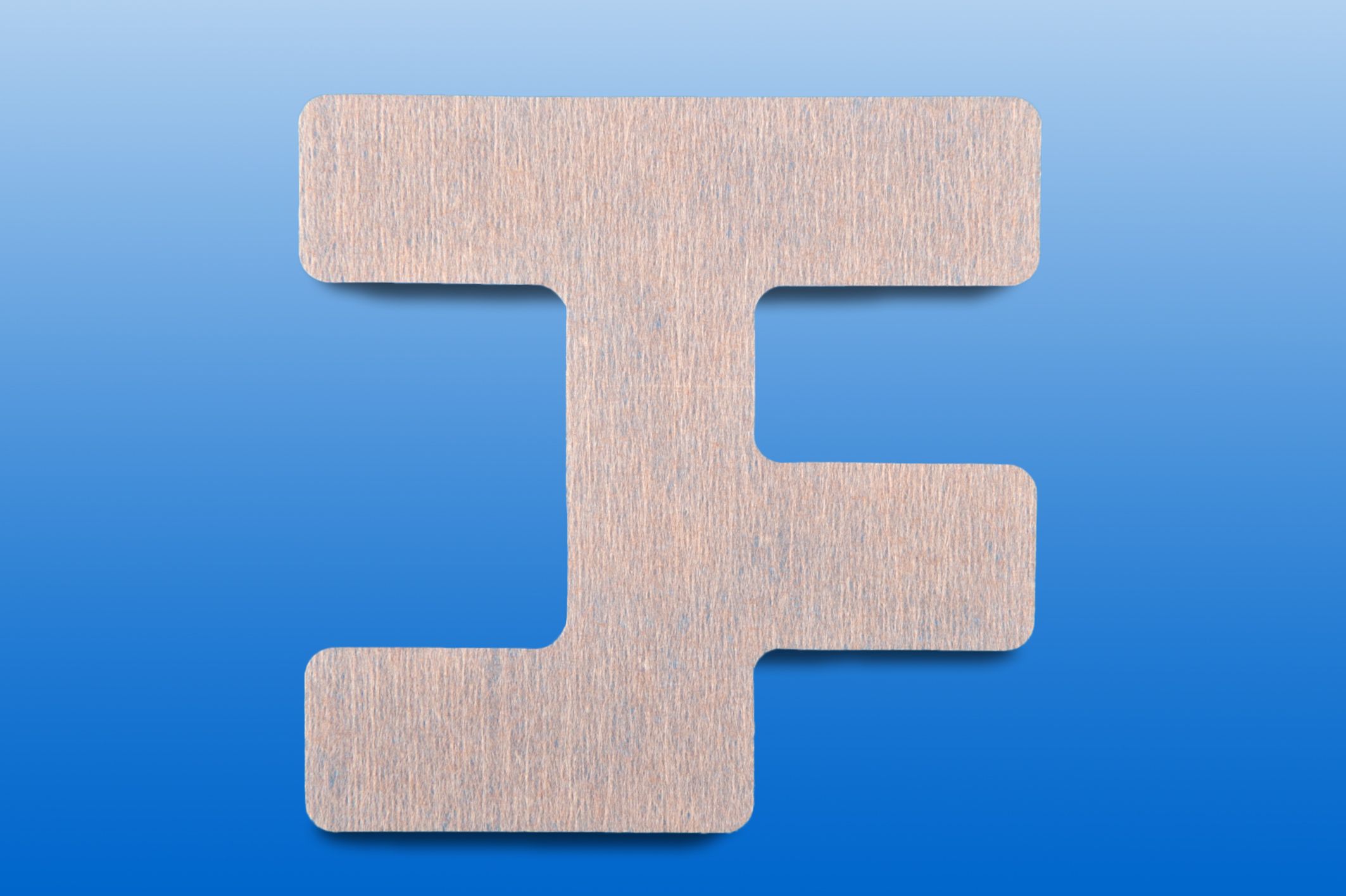 Hautfarbenes, T-förmiges Pflaster mit abgerundeten Ecken. Auf blauem Hintergrund.