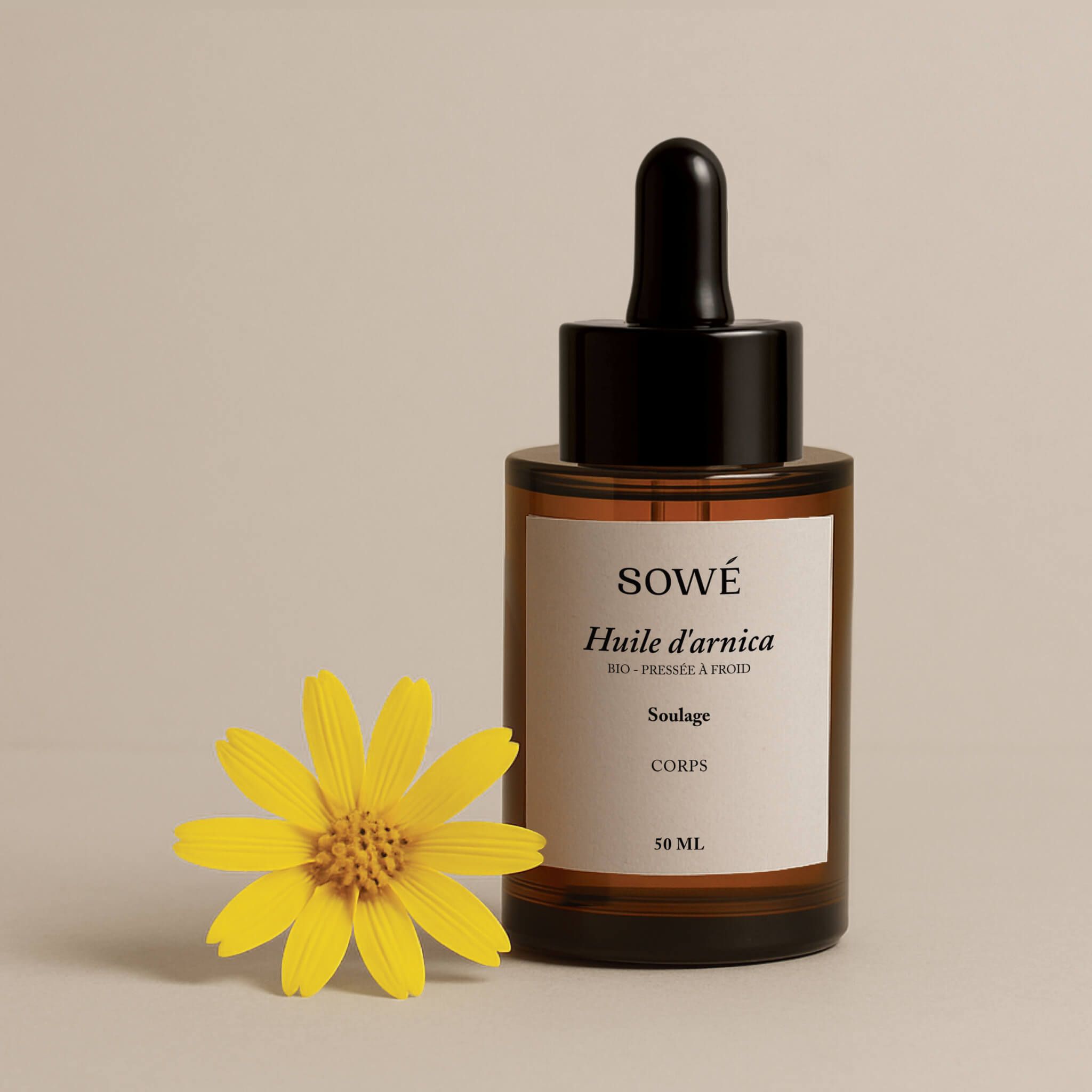 Braune Glasflasche mit Etikett und Pipette. Daneben eine gelbe Arnika-Blüte. Aufschrift: SOWÉ, Huile de arnica, 50 ml.
