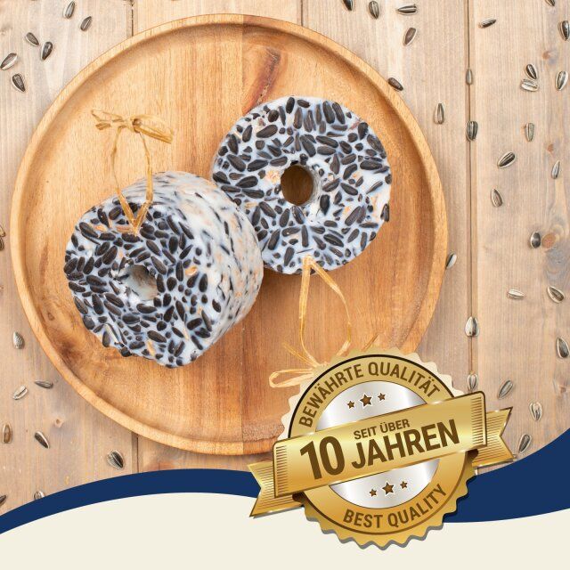 Zwei Lyra Pet® Riesenringe mit Sonnenblumenkernen auf einem Holztablett. Aufschrift: 'Bewährte Qualität seit über 10 Jahren'.
