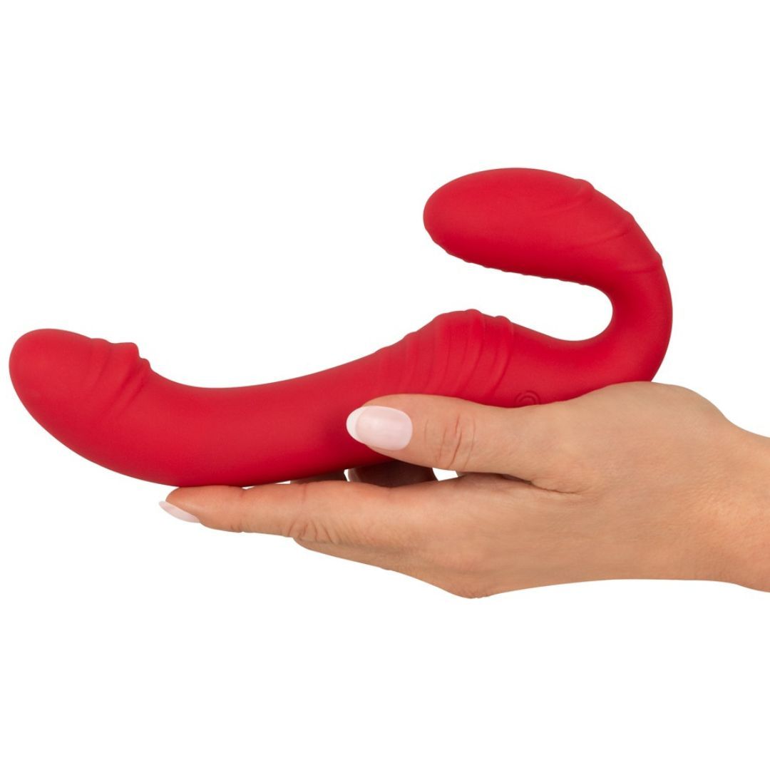 Roter Vibrator in einer Hand gehalten. Das Gerät hat eine gebogene Form mit zwei abgerundeten Enden.