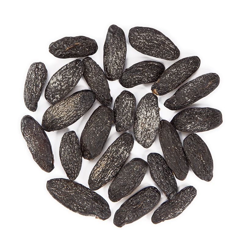 Dunkle, längliche Tonkabohnen, kreisförmig angeordnet auf weißem Hintergrund.