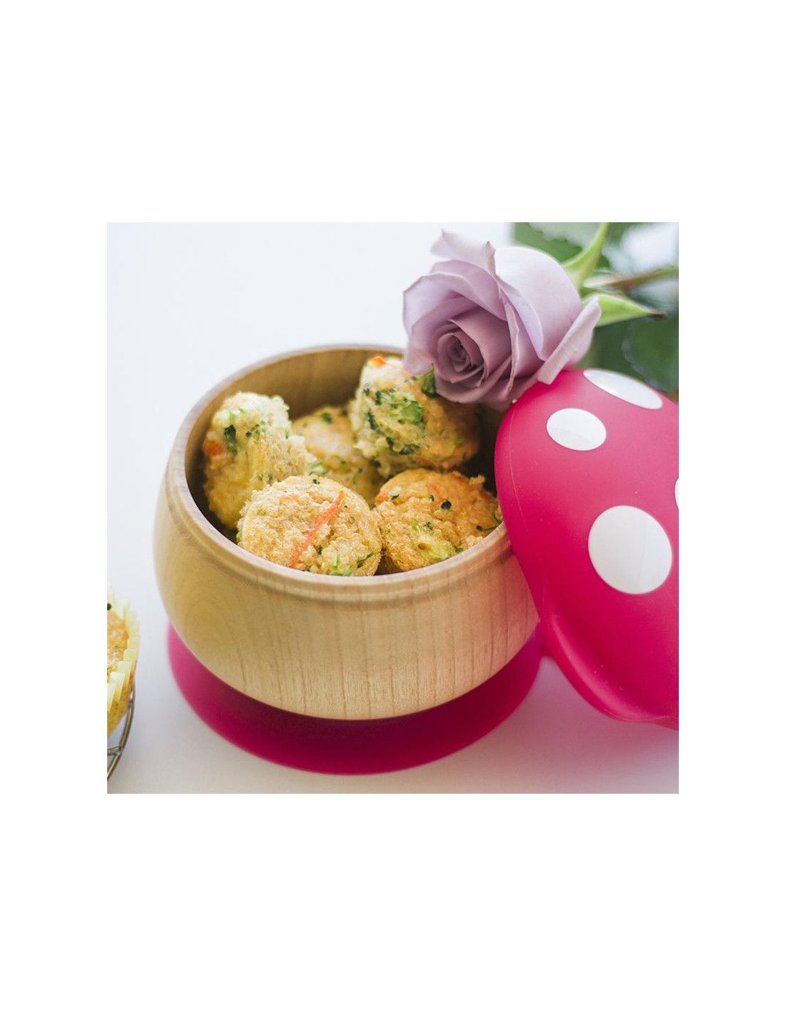 Holzschale mit Essen. Roter Saugnapf. Roter Deckel mit weißen Punkten. Rose daneben.