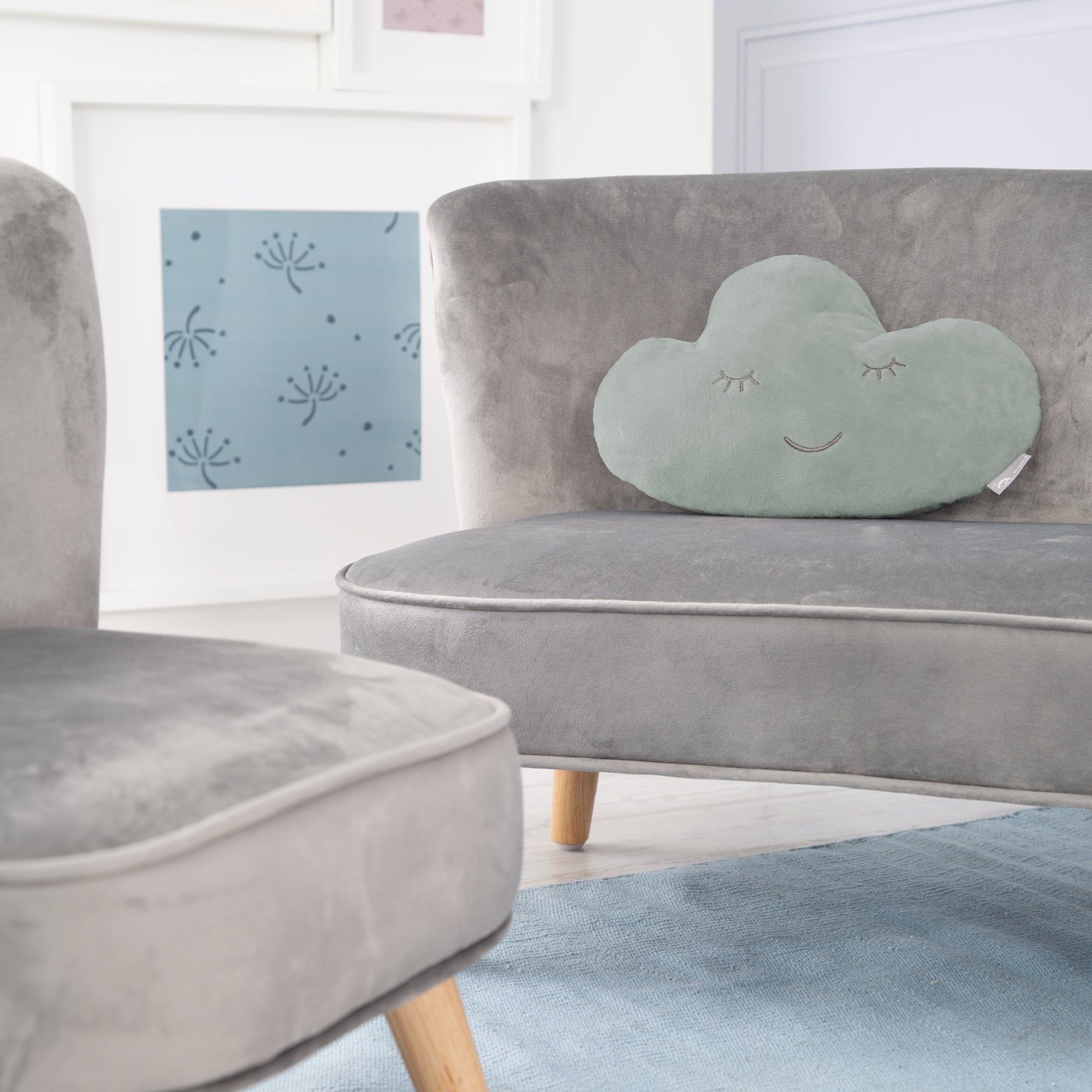 Hellgrünes Wolkenkissen auf grauem Sofa. Aufgestickte Augen und Mund. Marke roba.
