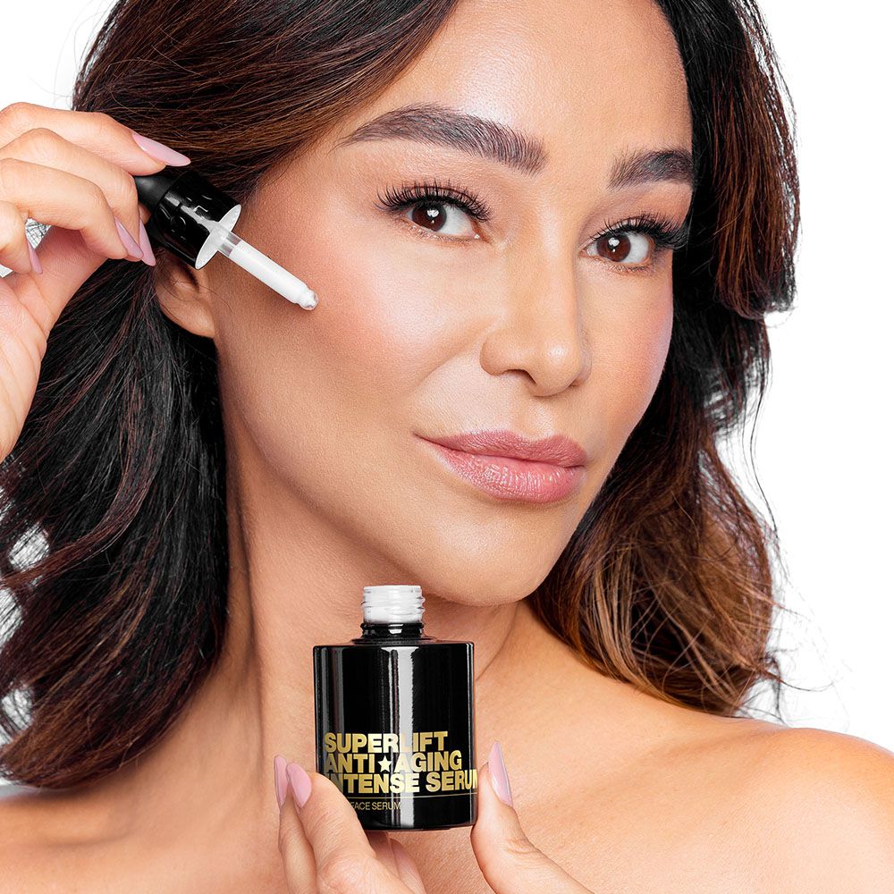 Frau hält Serumflasche mit Pipette. Schwarze Flasche mit goldfarbenem Text: Superlift Anti-Aging Intense Serum. Vegan Face Serum.