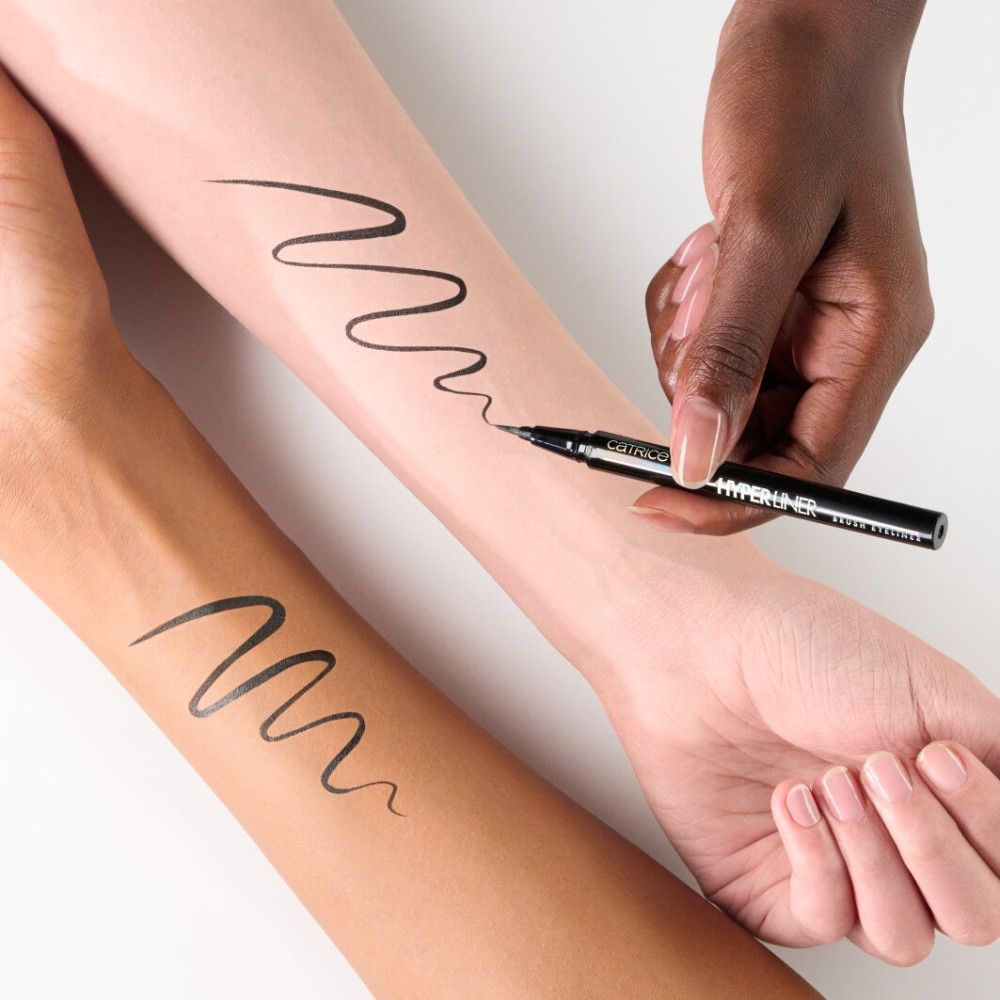 Hände zeichnen Linien mit schwarzem Eyeliner auf Arme. Der Eyeliner ist sichtbar.