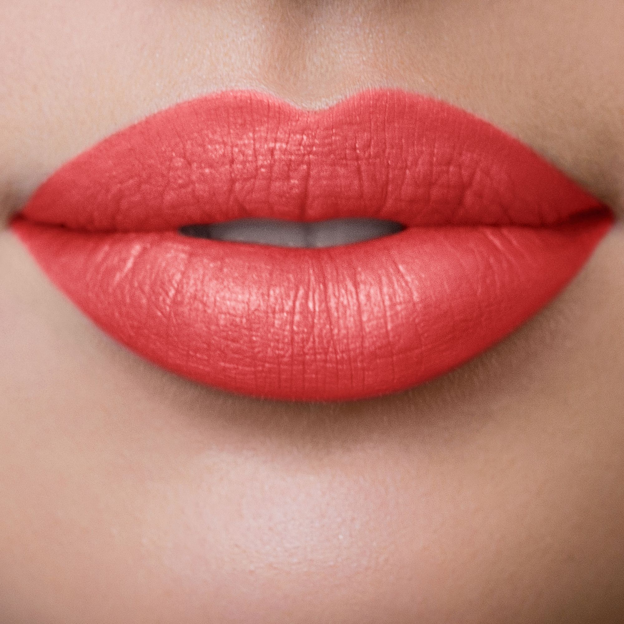 Nahaufnahme von Lippen, die mit korallenfarbenem Lippenstift geschminkt sind.