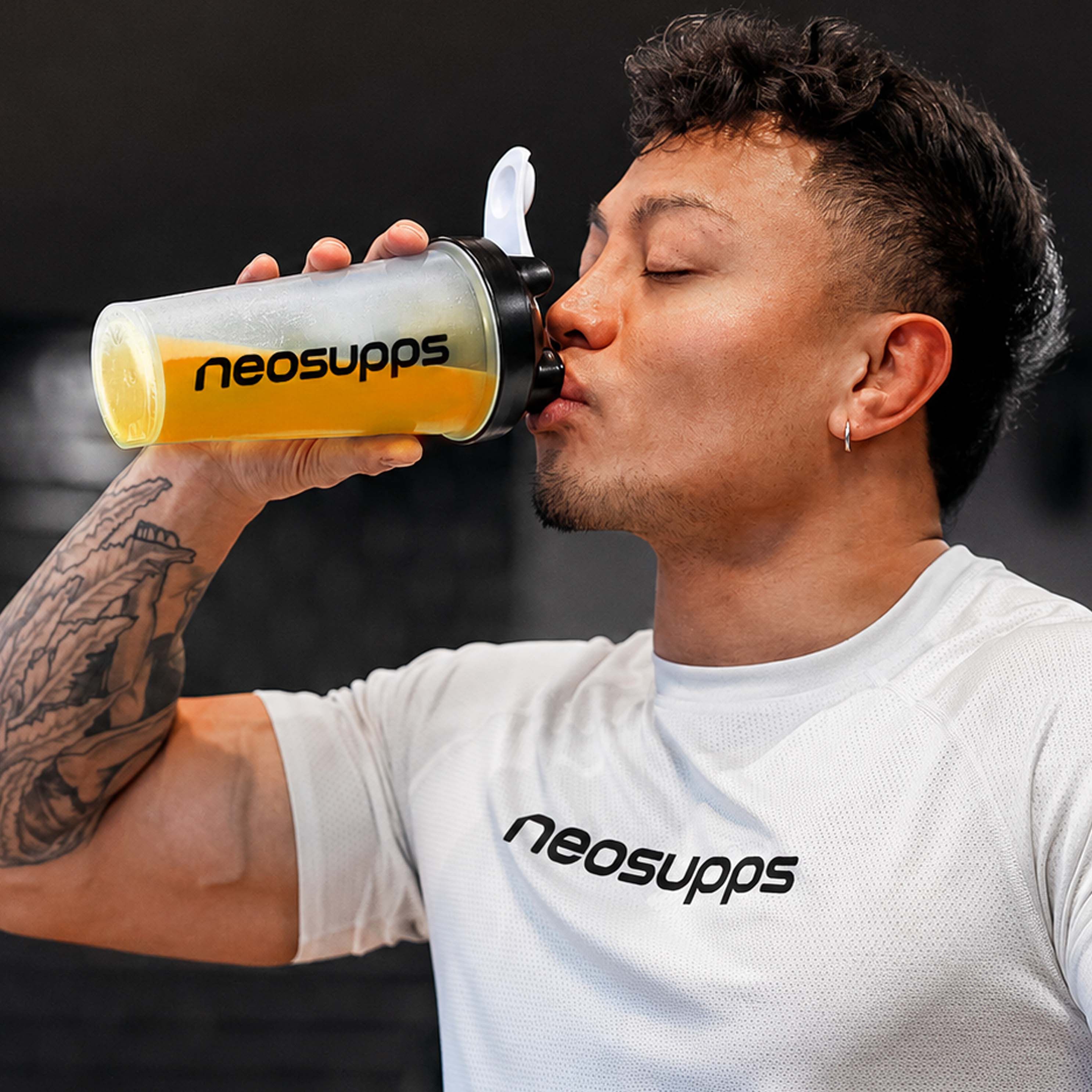 Mann trinkt aus einem Shaker mit "neosupps" Logo. Getränk: gelb. Produkt: Terminus Booster.