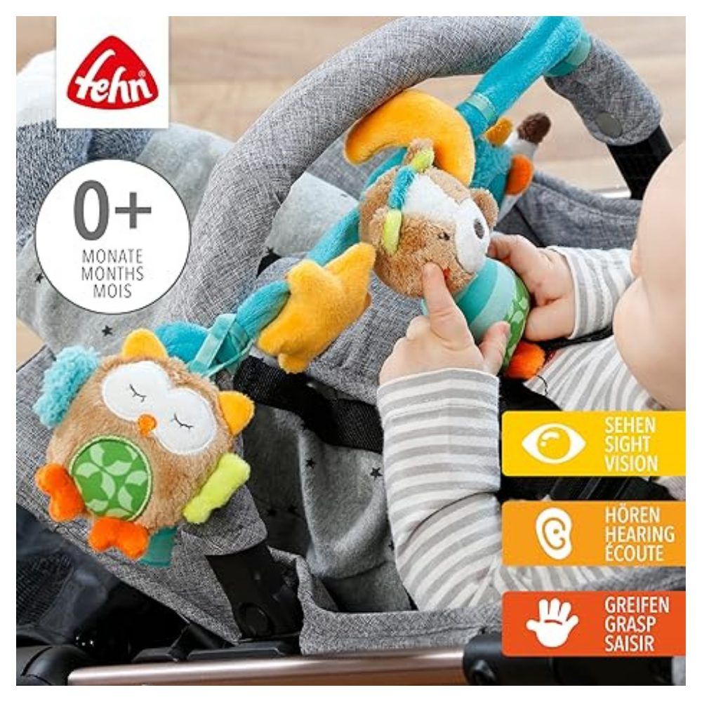 Kinderwagenkette mit Stofftieren. Baby berührt Spielzeug. Marke 'fehn' und Altersempfehlung '0+ Monate' sichtbar.