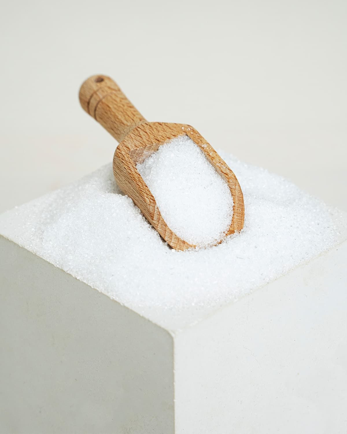 Holzlöffel mit weißem Pulver auf einem weißen Würfel.
