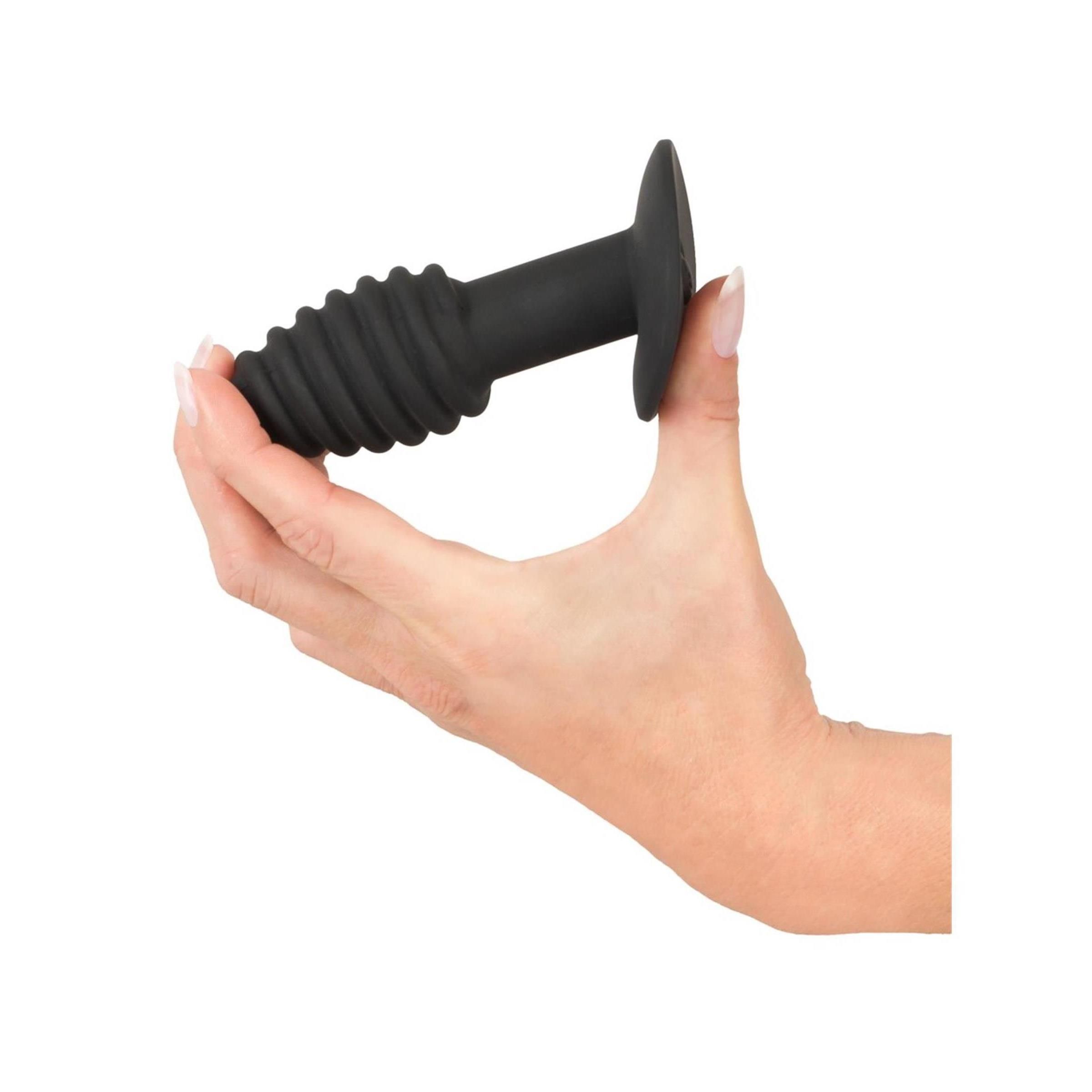 Schwarzer Analplug mit spiralförmigem Design, gehalten in einer Hand. Basis und Schaft sind zylindrisch, der Kopf ist konisch.