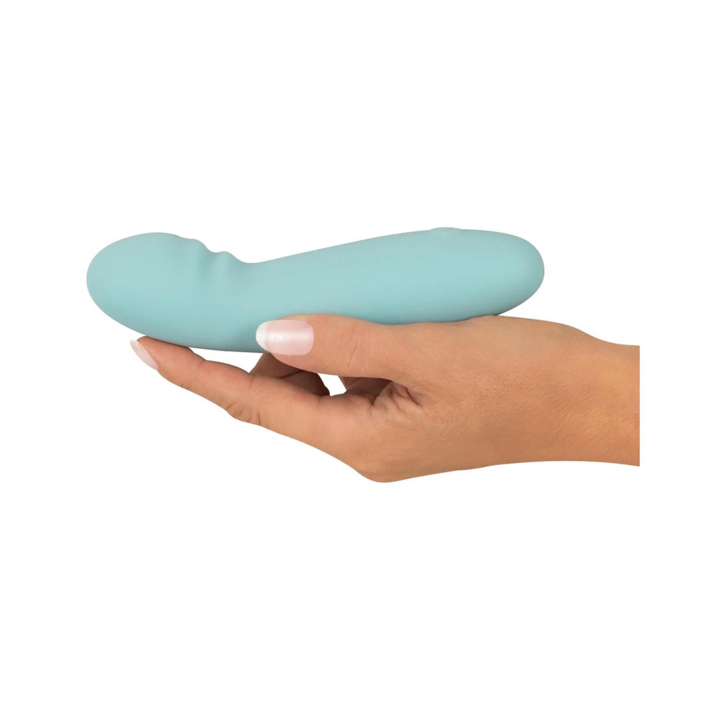 Türkisfarbener Vibrator in einer Hand gehalten. Ergonomische Form, abgerundete Spitze.
