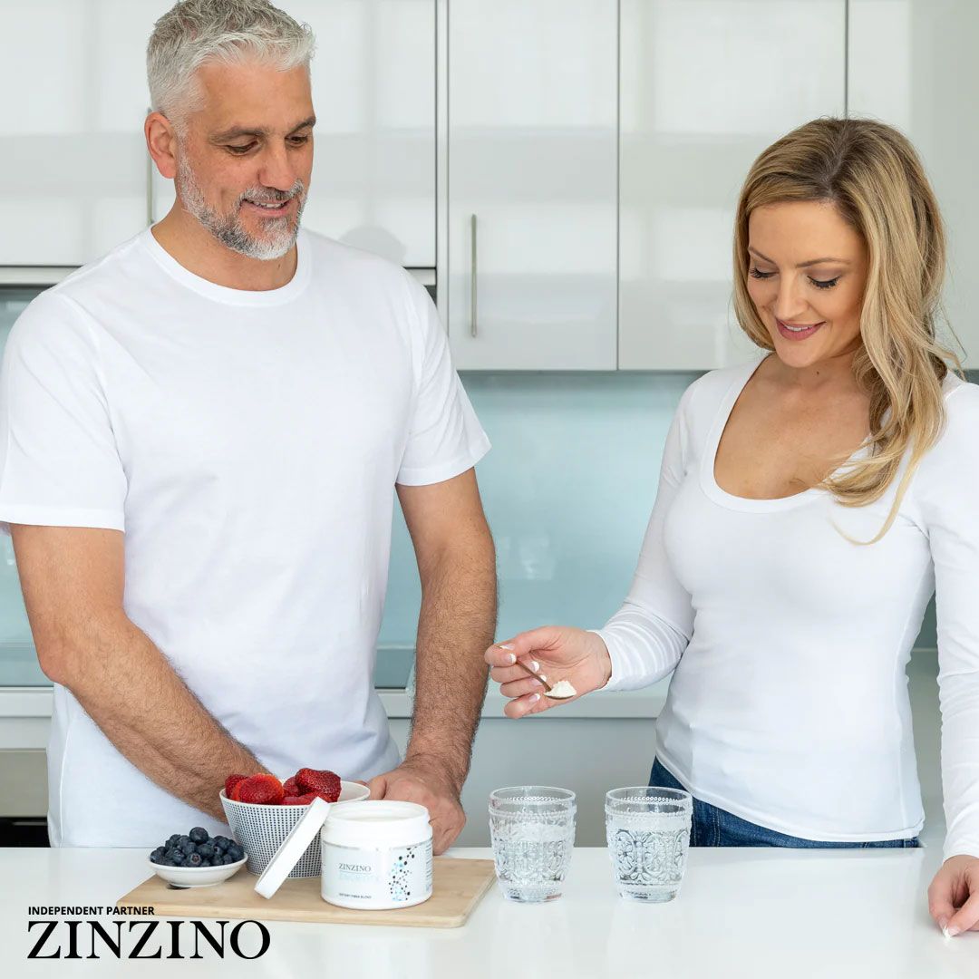 Paar in weißem T-Shirt und Bluse. Auf dem Tisch: ZINZINO ZinoBiotic+ Dose, Beeren, Gläser mit Wasser.
