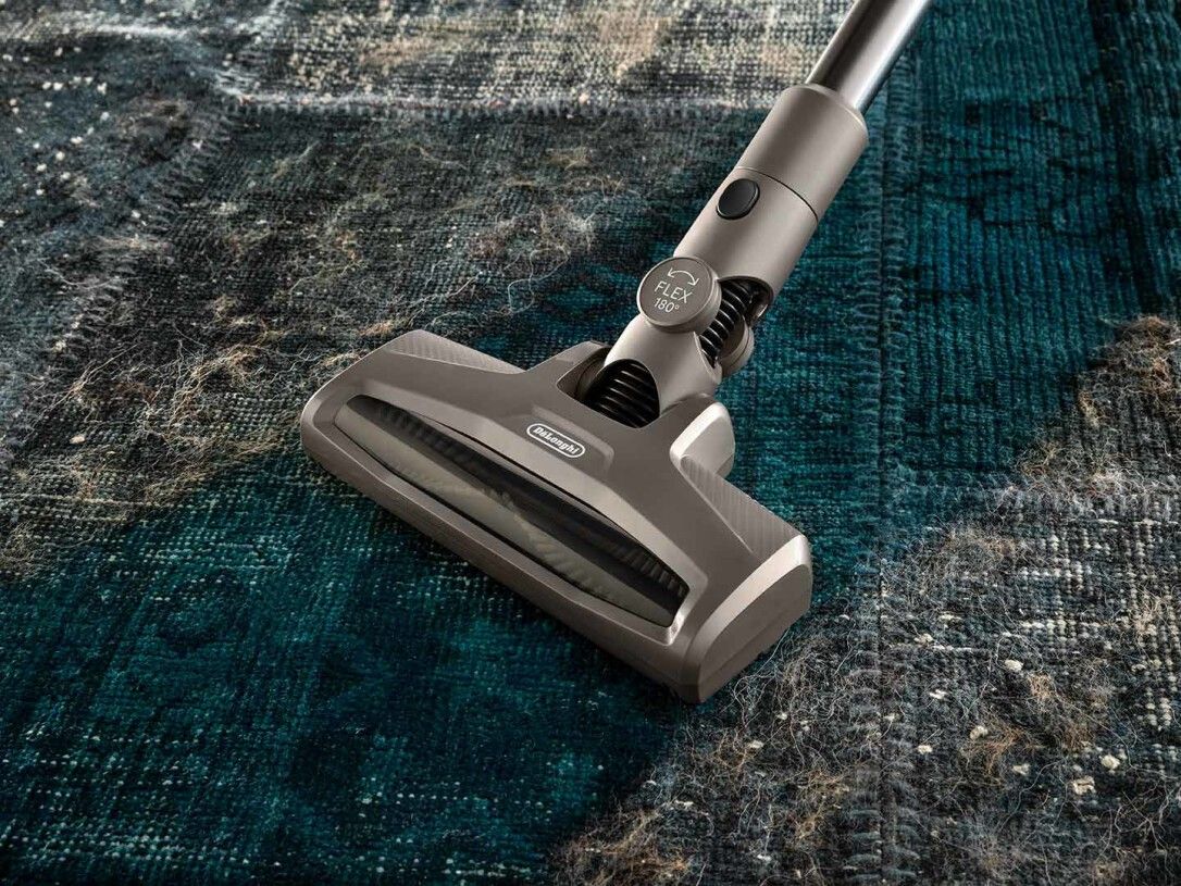 Nahaufnahme des Staubsaugerkopfes auf einem Teppich. Der Kopf ist grau, mit dem Logo von Delonghi.