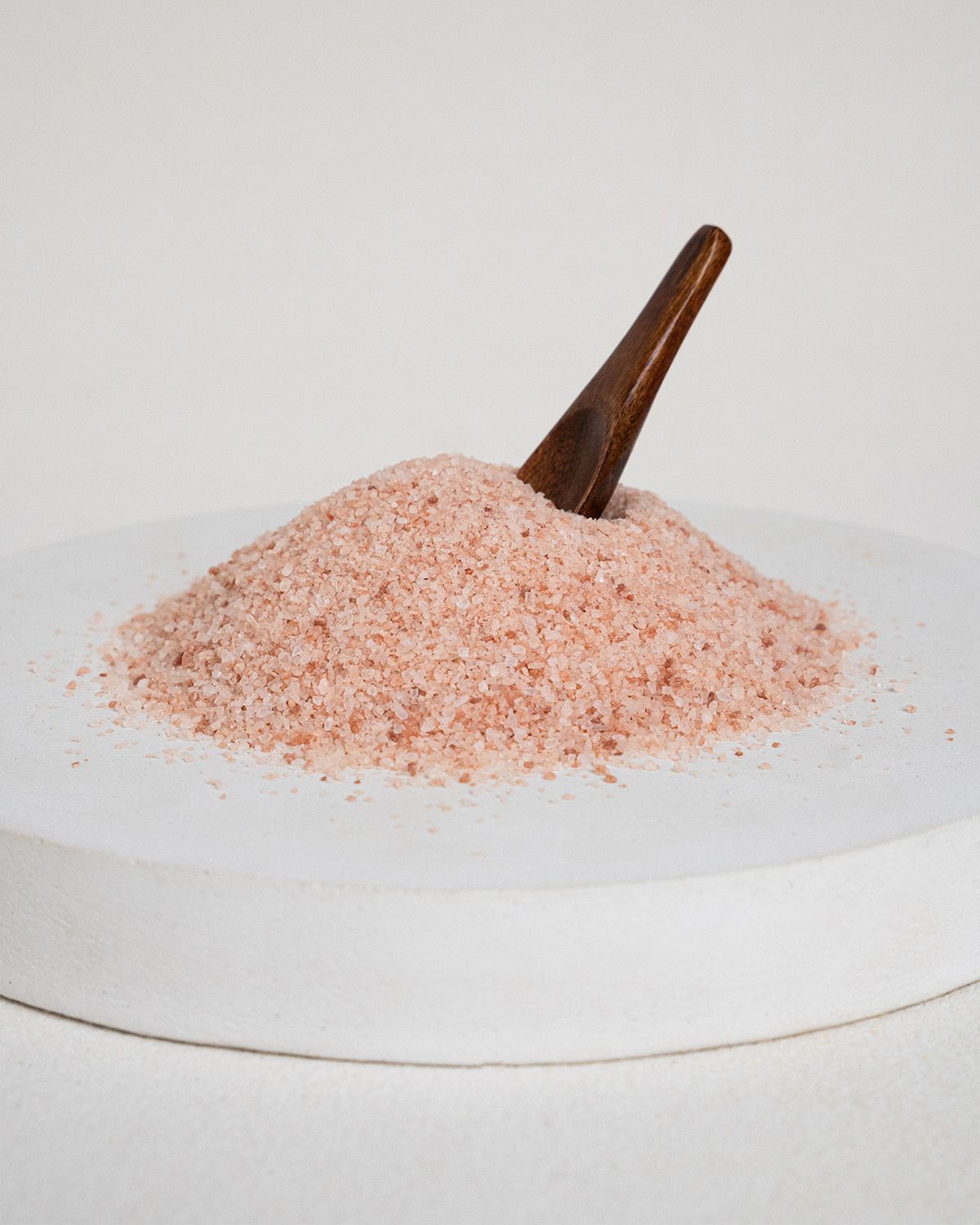 Himalaya-Salz, fein, auf einem weißen Stein mit Holzlöffel.