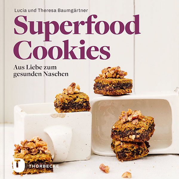 Buchcover mit Titel "Superfood Cookies". Autoren: Lucia und Theresa Baumgärtner. Gezeigt werden quadratische Kekse mit Nüssen.