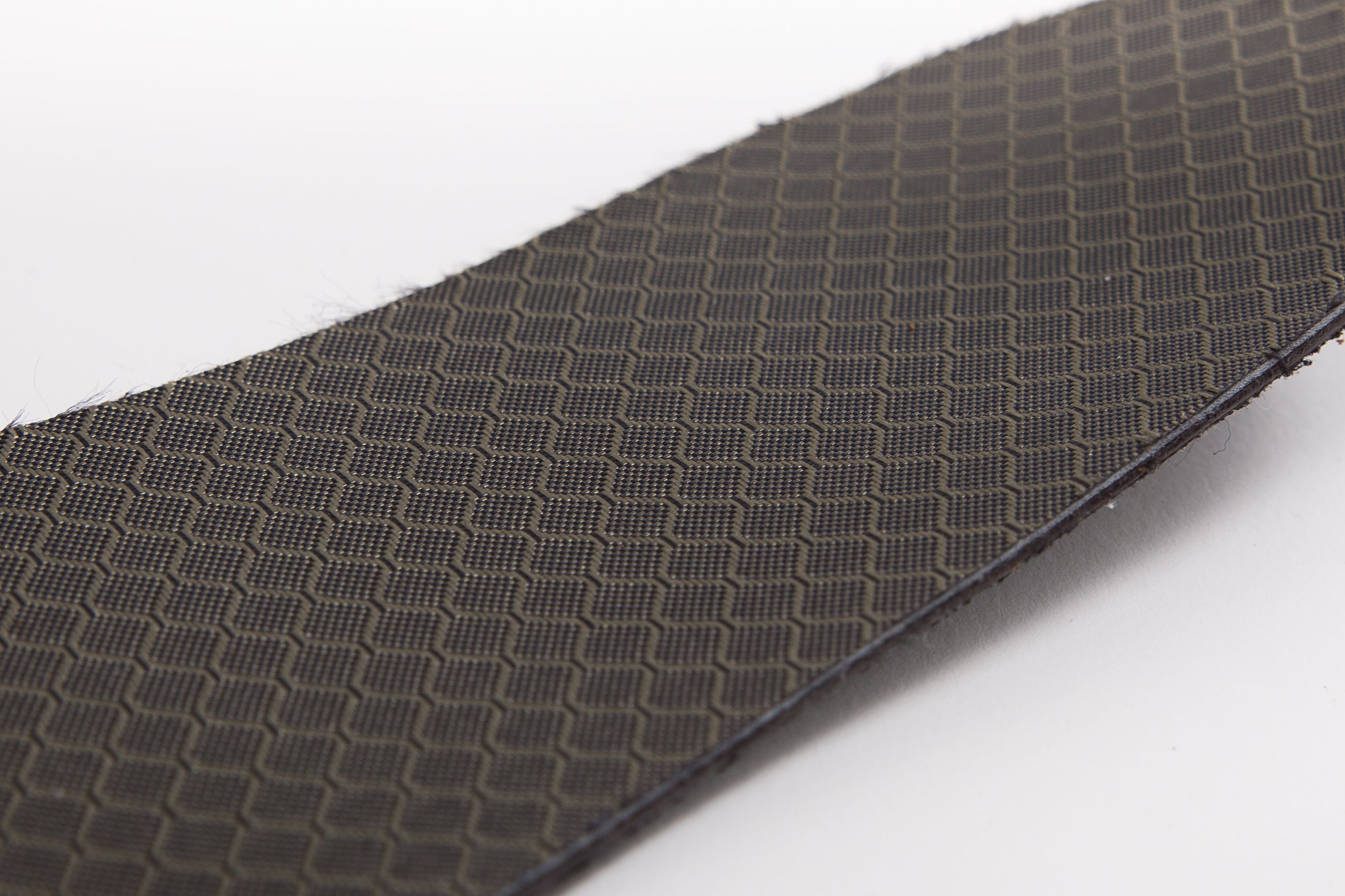 Nahaufnahme eines schwarzen, strukturierten Materials. Das Muster besteht aus kleinen, quadratischen Elementen.