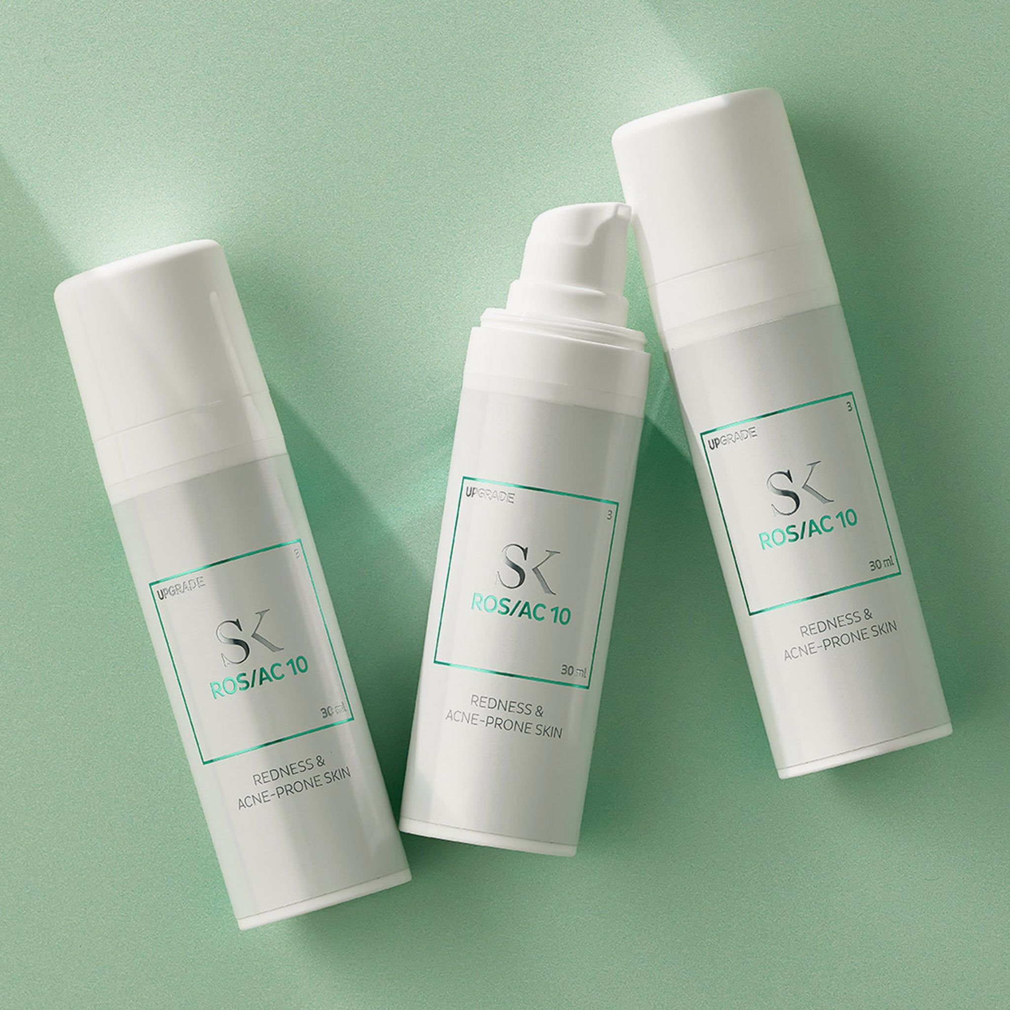 Drei weiße Flaschen mit grünem Etikett. Aufschrift: SK ROS/AC 10, Redness & Acne-Prone Skin. 30 ml.