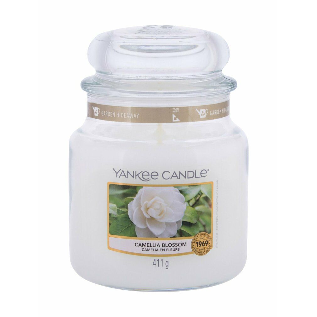 Weißes Kerzenglas mit Deckel. Etikett mit Blüte und Schriftzug. Aufschrift: Yankee Candle, Camellia Blossom, 411g.