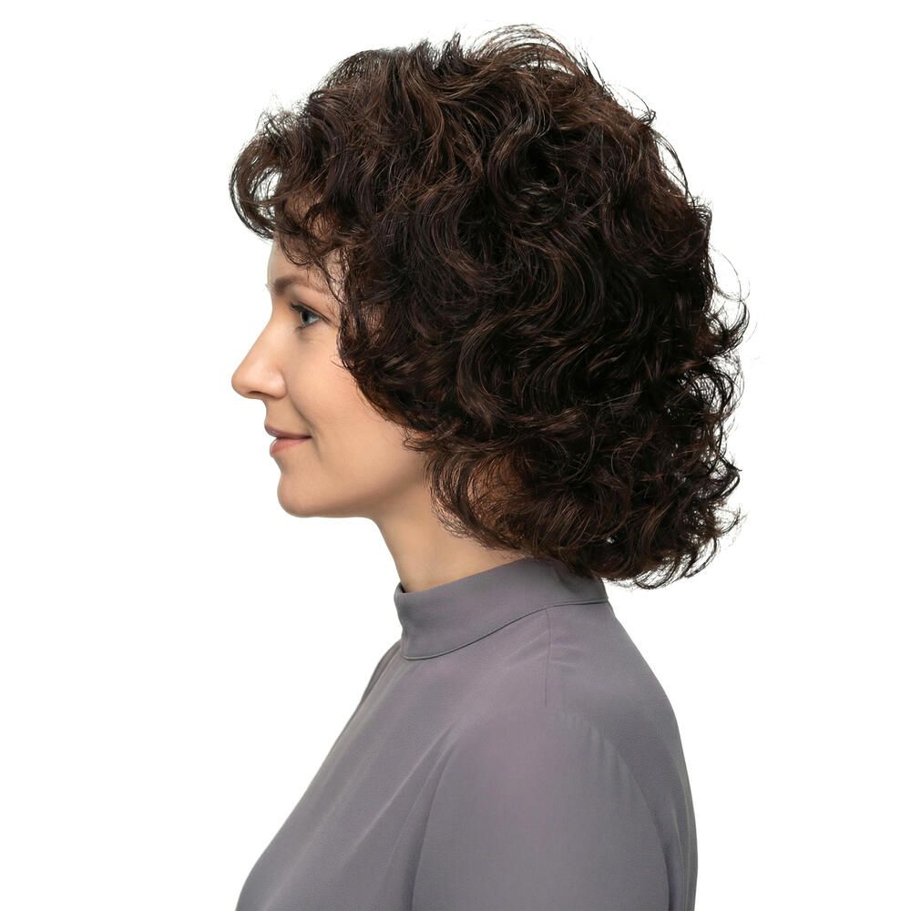 Frau mit brauner, lockiger Perücke. Profilansicht. Graues Oberteil.