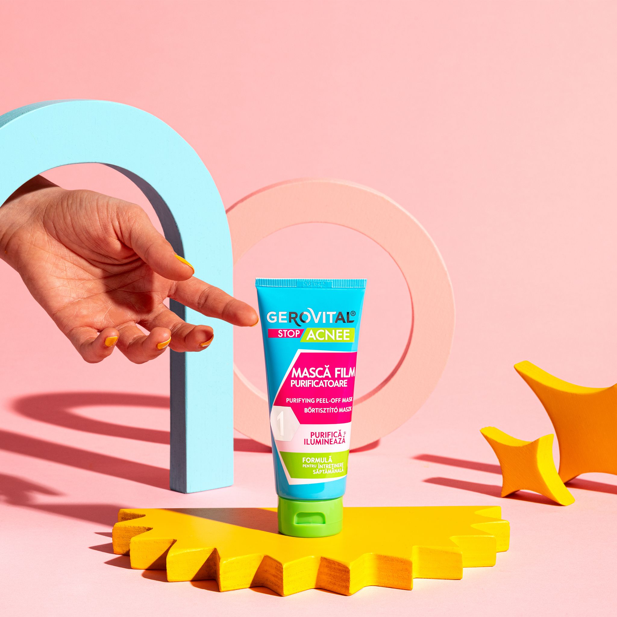 Hand zeigt auf eine blau-grüne Tube. Text: Gerovital Stop Acnee, Mască Film Purificatoare, Purifying Peel-off Maske.