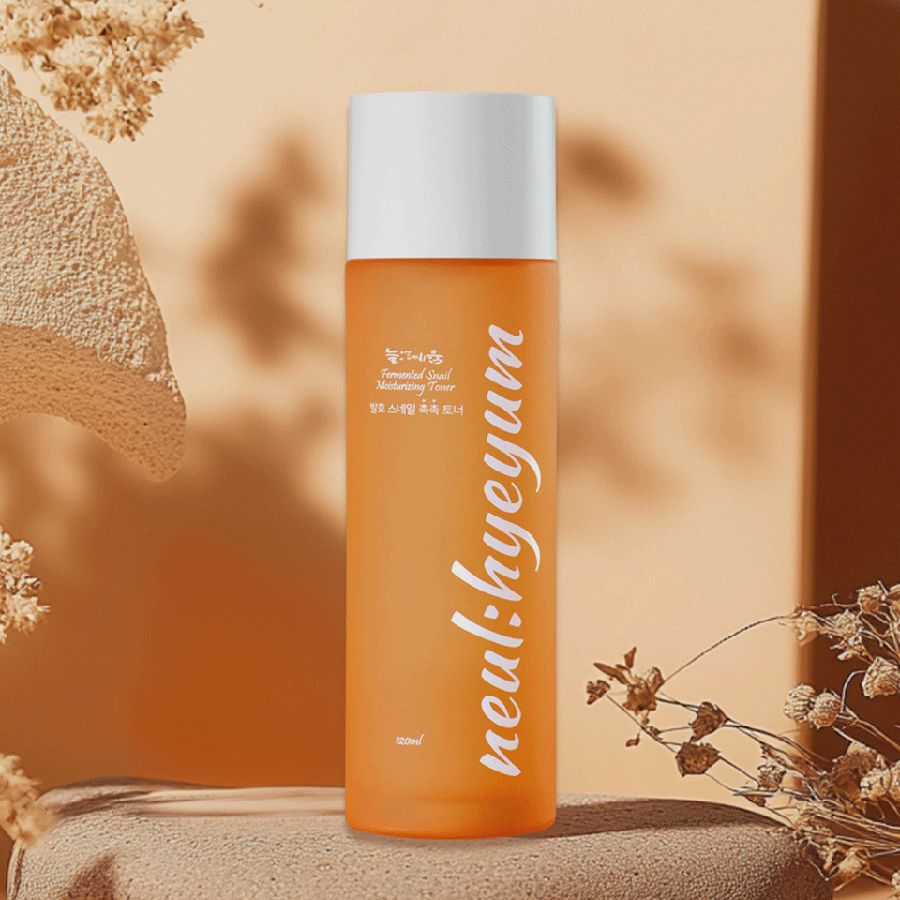 Orangefarbene Flasche mit weißem Deckel auf einem Podest. Aufschrift "neul:hyeyum" in weißer Schrift.