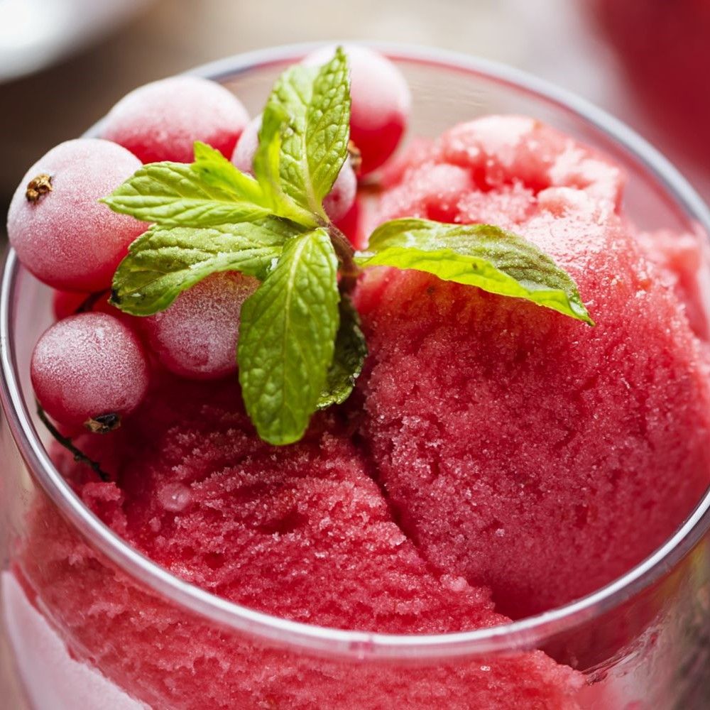 Glas mit rosa Eiscreme, roten Johannisbeeren und Minze. Nahaufnahme.