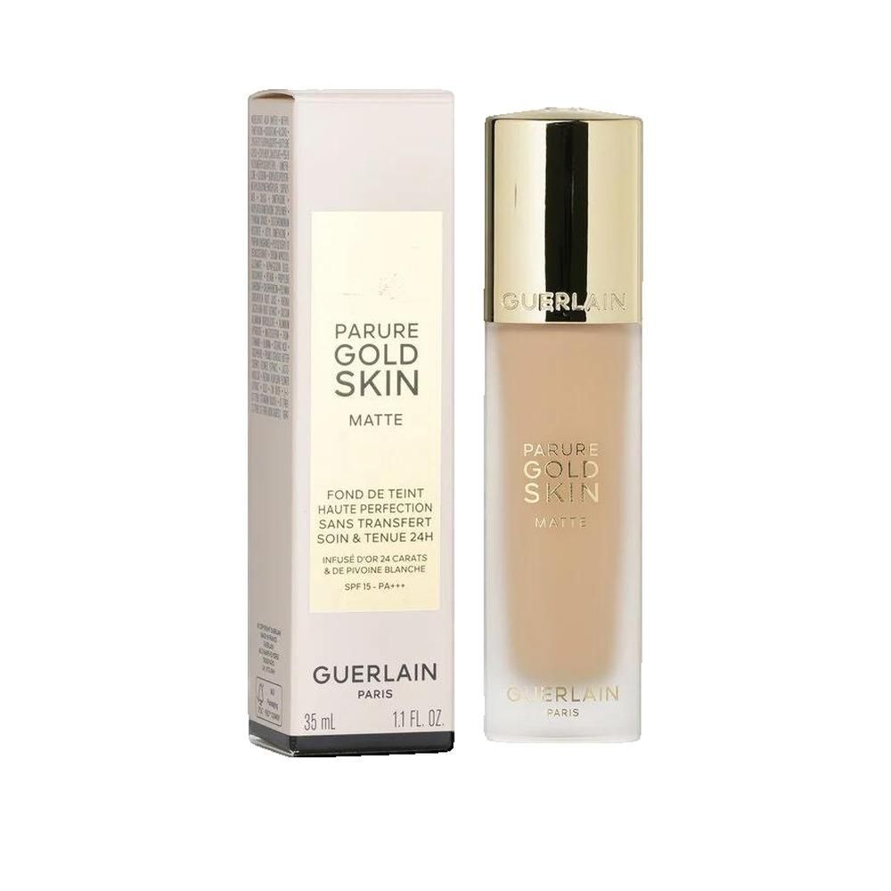 Foundation-Flakon und Verpackung. Aufschrift: 'Parure Gold Skin Matte'. Enthält 24 Karat Gold und weißen Pfirsich. SPF 15. Marke Guerlain.