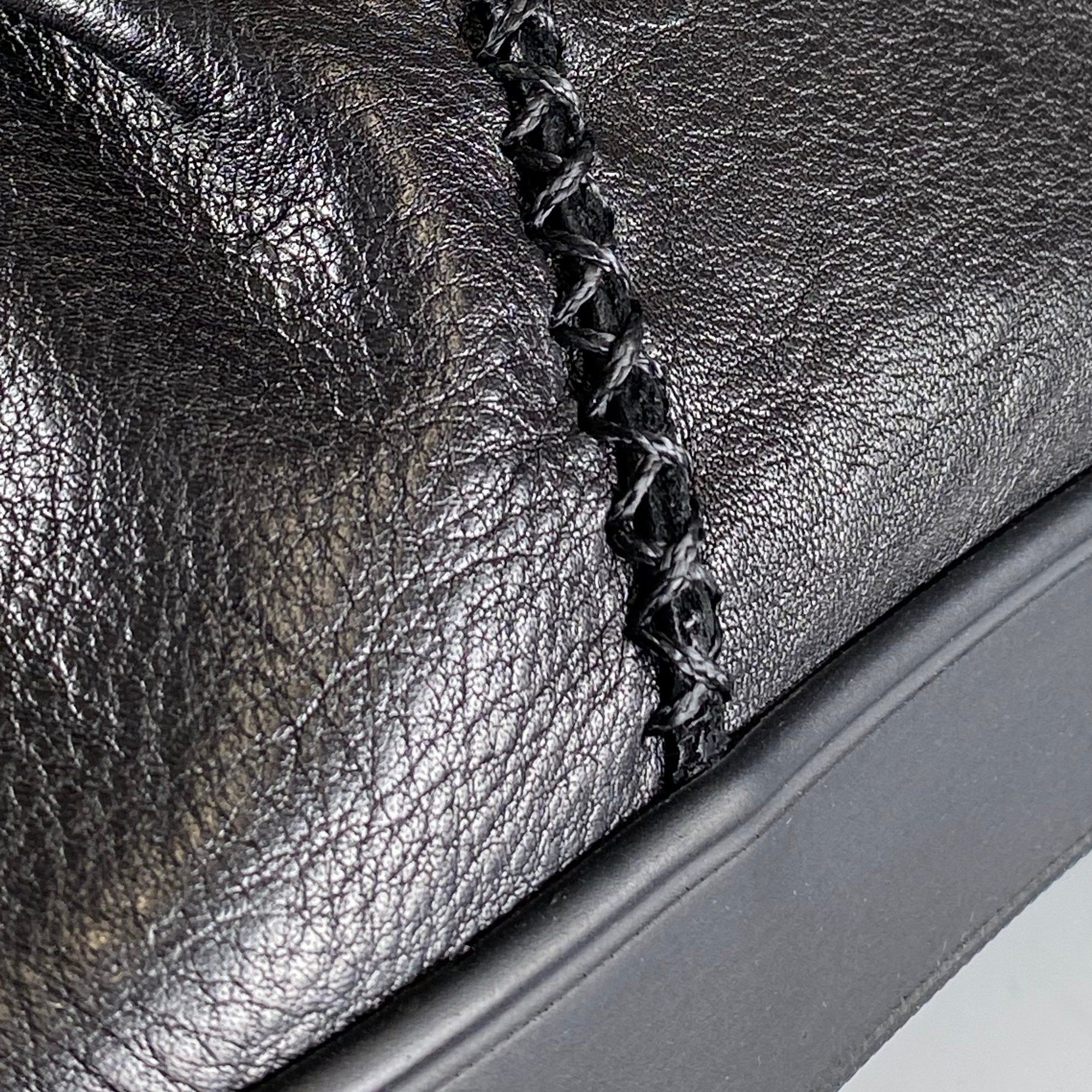 Nahaufnahme einer schwarzen Stiefelette. Ziernähte und Textur des Leders sind deutlich sichtbar. Flache Sohle.