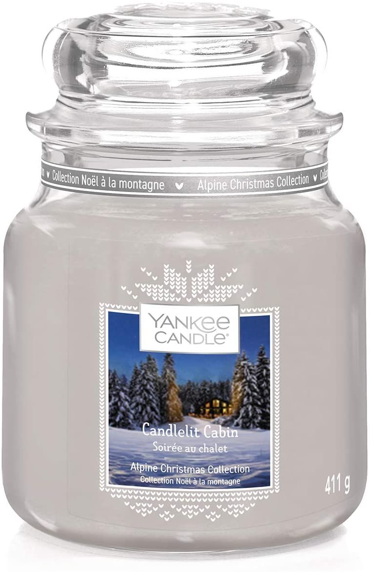 Kerzenglas mit Deckel, Etikett mit Winterlandschaft. Text: Yankee Candle, Candlelit Cabin, 411g.