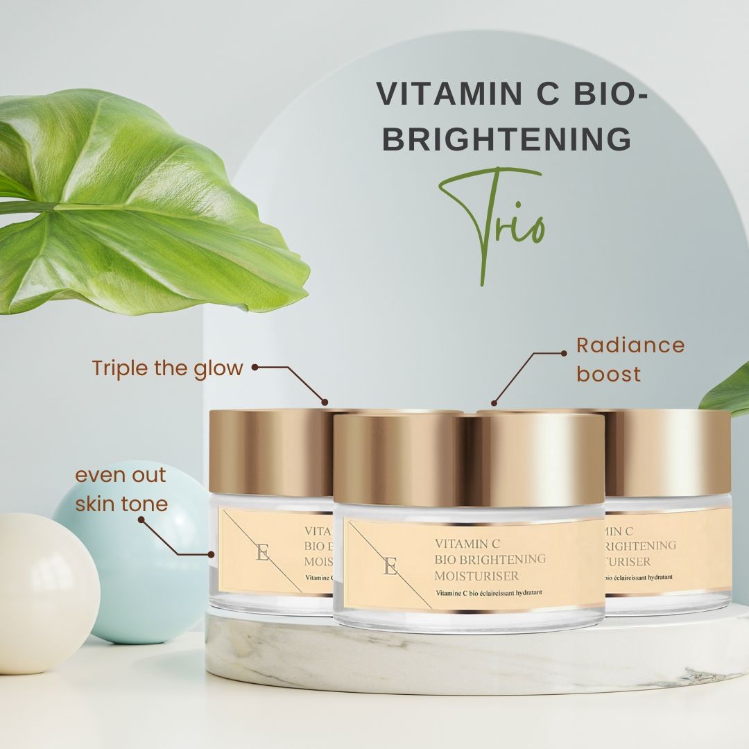 Drei Tiegel mit goldfarbenen Deckeln. Auf den Etiketten steht: Vitamin C Bio Brightening Moisturiser. Text: Trio, Radiance boost, even out skin tone.