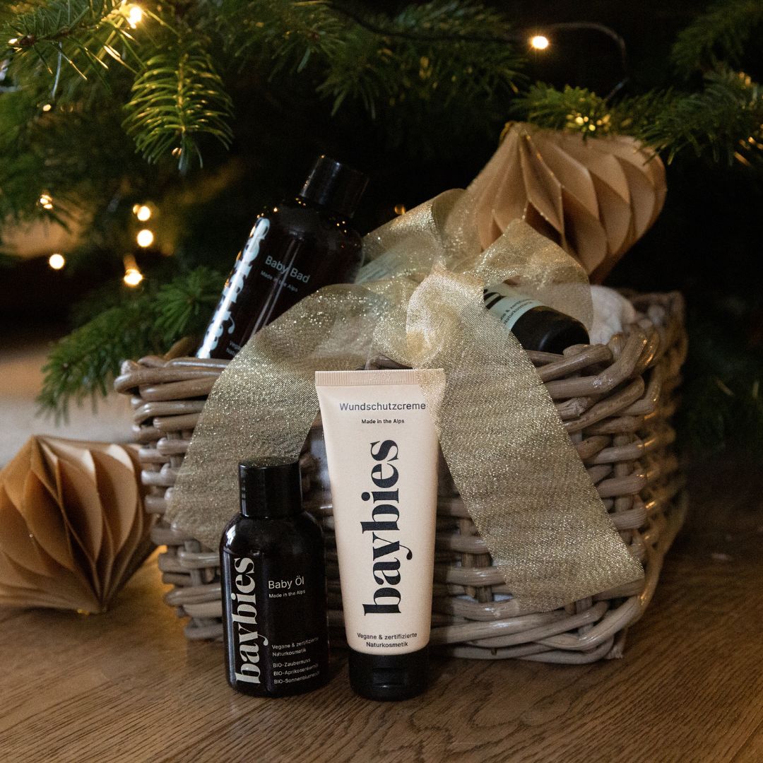 Geschenkset mit Babyprodukten in einem Weidenkorb. Enthält Öl, Lotion und Creme. Mit goldener Schleife verziert.
