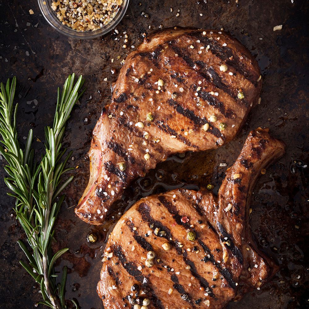 Zwei gegrillte Steaks mit Pfeffer. Rosmarinzweig und Gewürzschale.