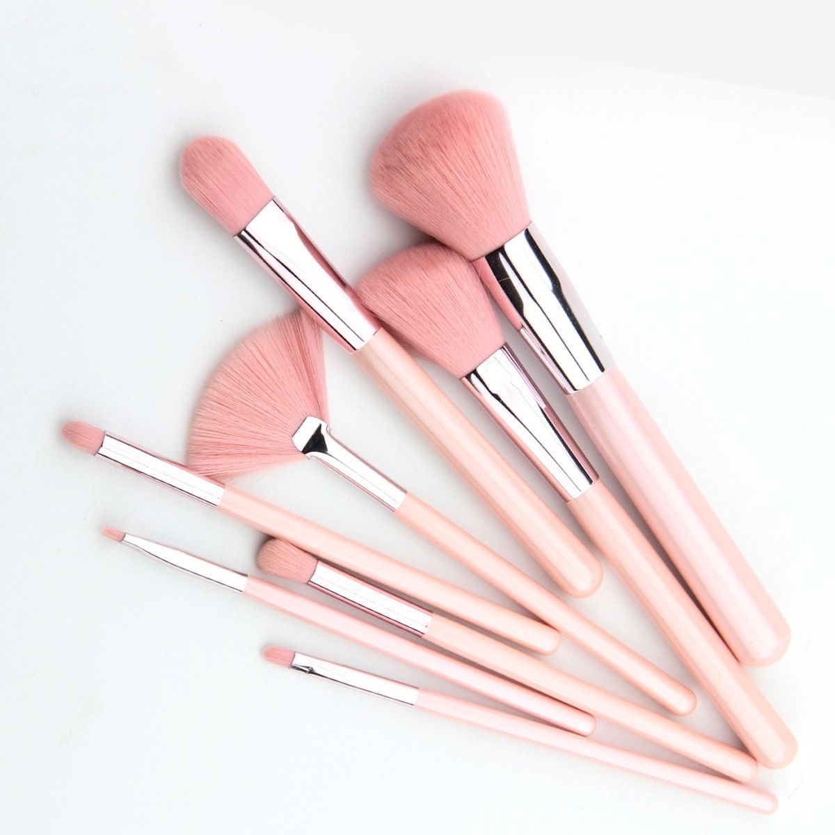 Ein Set aus acht rosa Make-up-Pinseln, auf weißem Hintergrund angeordnet.