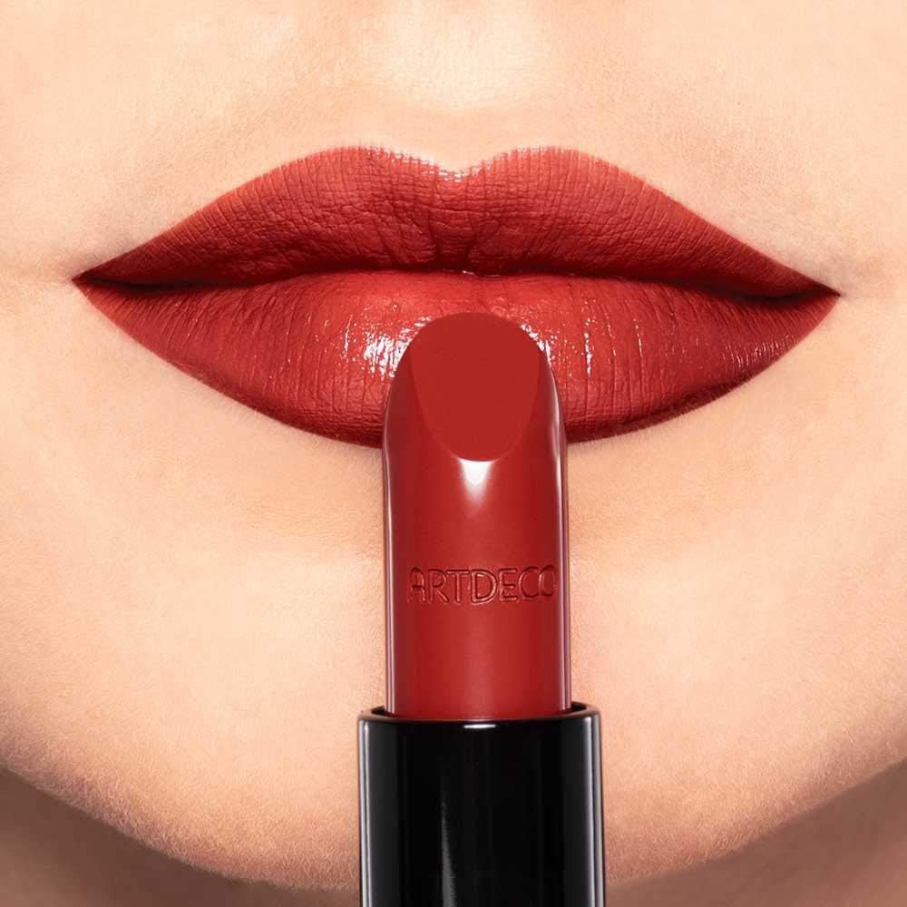 Roter Lippenstift vor Lippen. Marke Artdeco auf dem Lippenstift.