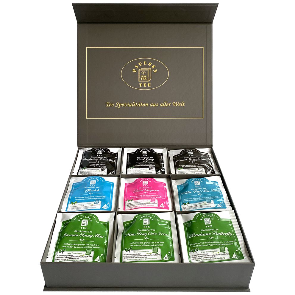 Geschenkbox mit Teebeuteln. Neun Pyramidenbeutel in einer geöffneten, grauen Box. Logo und Text auf dem Deckel.