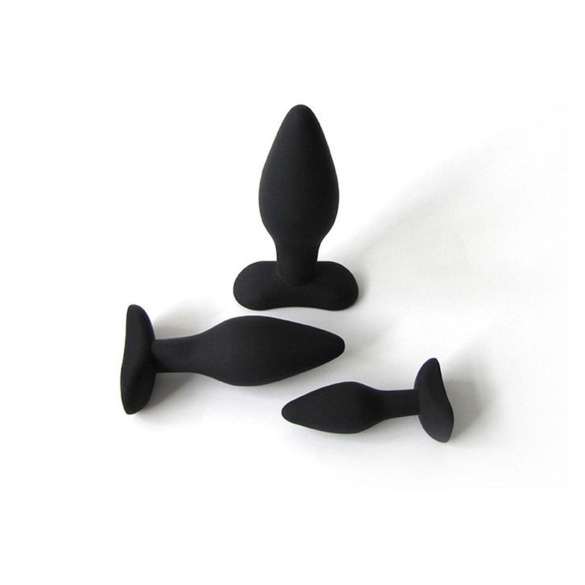 Drei schwarze Anal-Plugs. Unterschiedliche Größen, konische Form, breite Basis. Auf weißem Hintergrund.