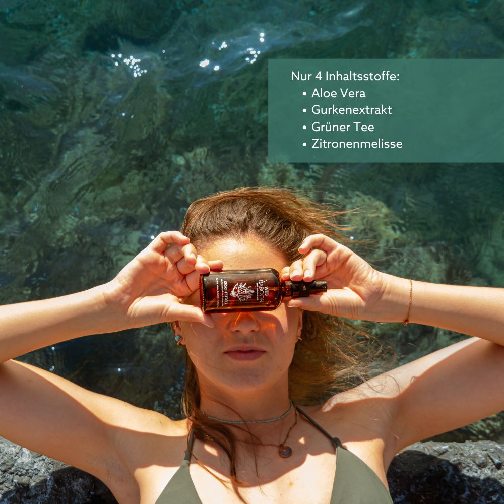 Braune Sprühflasche. Aufschrift: Wild Baboon. Enthält Aloe Vera, Gurkenextrakt, grünen Tee und Zitronenmelisse. Frau hält die Flasche vor die Augen.
