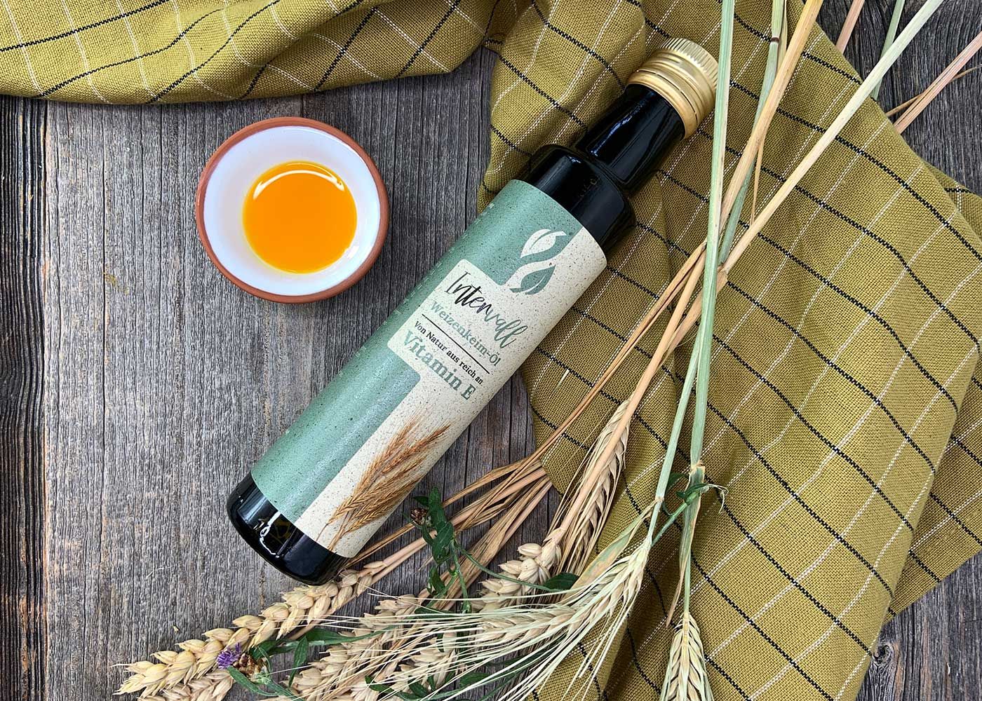 Produktflasche und Schale mit Öl auf einem karierten Tuch und Dekoration. Flasche mit Etikett.